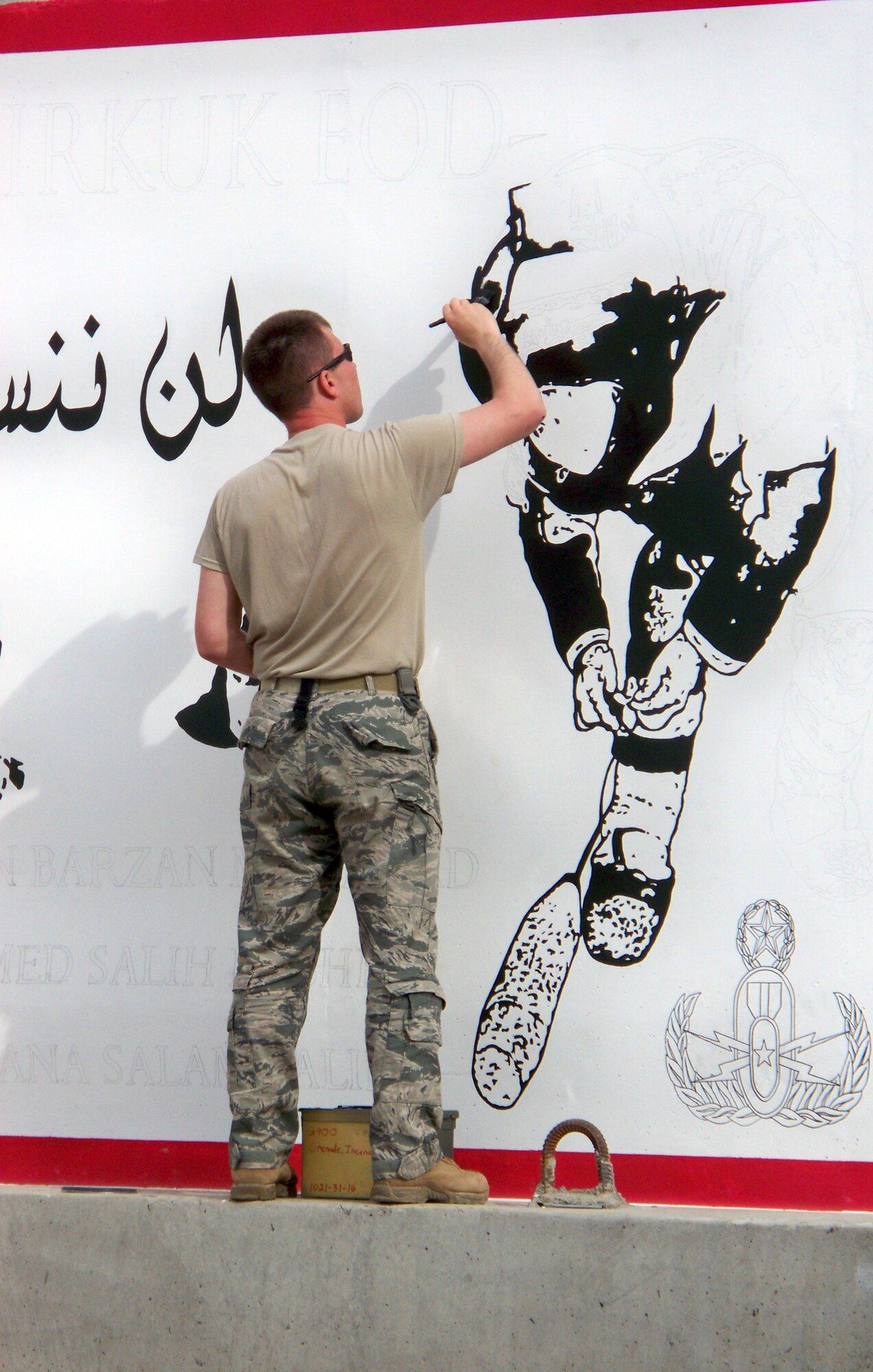 Tech. Sgt. Eric Eberhard paints a mural on one of the concrete walls to honor three fallen Iraqi police counter explosive team members for an unveiling ceremony held Feb. 23, 2010, at the explosive ordnance disposal compound at Kirkuk Air Base, Iraq. Sergeant Eberhard is a 506th Civil Engineer Squadron Explosive Ordnance Disposal team leader deployed from Hill Air Force Base, Utah. (Courtesy photo)