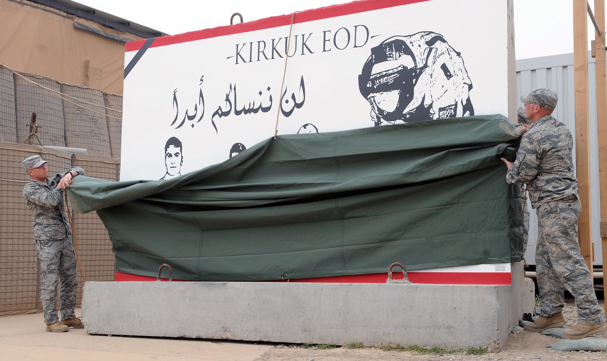 Members of the 506th Civil Engineer Squadron explosive ordnance disposal team memorialize three Iraqi police counter-explosive team members killed by an Aug. 12, 2009, vehicle-borne improvised explosive device by unveiling a mural painted in their honor Feb. 23, 2010, at the EOD compound at Kirkuk Air Base, Iraq. The families of the fallen were presented donated funds raised during an EOD bomb suit run. (U.S. Air Force photo/Staff Sgt. Tabitha Kuykendall)