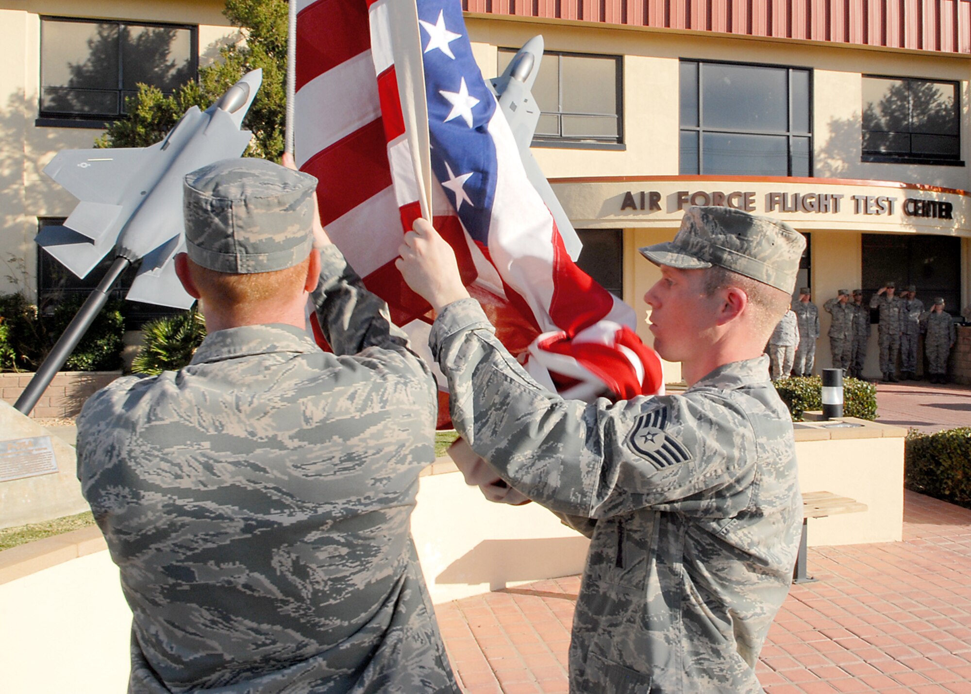Members of the 412th Maintence Squadron lower the American Flag during Edwards monthly retreat ceremony at the Air Force Flight Test Center Headquarters Feb. 25. A retreat ceremony marks the end of the duty day and honors the American Flag. (Air Force photo/Airman 1st Class William A. O'Brien)