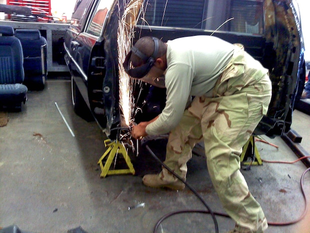 Senior Airman Phillip Robinson grinds off sharp edges on the chassis of a hearse which was converted into a mobile training aid for the base honor guard here recently. Airman Robinson worked with 22 other vehicle maintainers to accomplish the project during several weeks of work on their off-duty time. Airman Robinson is a special vehicle maintainer with the 628th Logistics Readiness Squadron. (Courtesy photo)