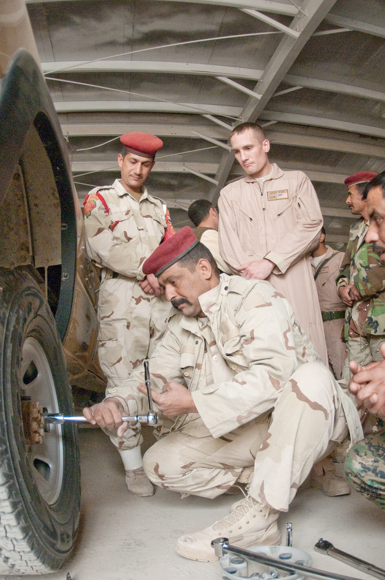 Staff Sgt. Giles Fish observes Iraqi army members change a tire during a training course given by the Logistics Military Advisory Team Feb. 22, 2010, at Camp Ur, Iraq. Sergeant Fish is assigned to the 407th Expeditionary Logistics Readiness Squadron at Ali Base, Iraq. He is deployed from Little Rock Air Force Base, Ark. (U.S. Air Force photo/Senior Master Sgt. Elizabeth Gilbert)