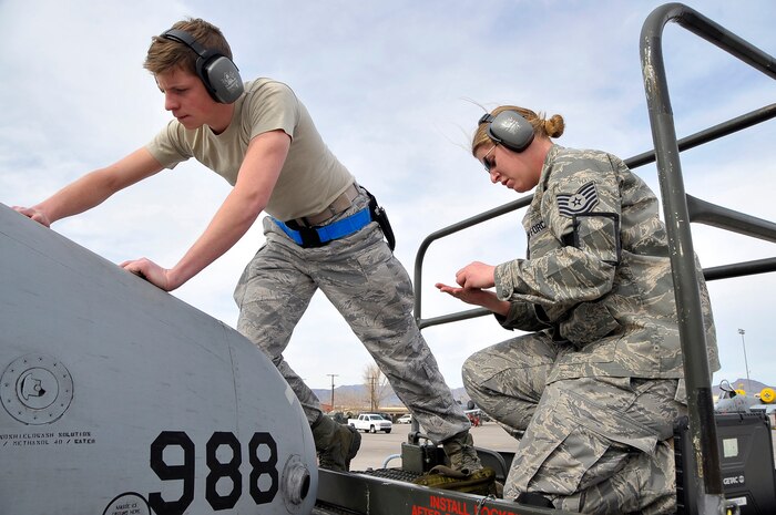 NELLIS AIR FORCE BASE, Nev. -- Airman 1st Class Gregory Beach is assisted by Tech. Sgt. Lisa Bowers, both from the 52nd Aircraft Maintenance Squadron, Spangdahlem Air Base, Germany, in repairing a fuel door on an A-10 Warthog during Red Flag 10-3 Feb. 26. Red Flag is a realistic combat training exercise involving the air forces of the United States and its allies. The exercise is conducted on the 15,000-square-mile Nevada Test and Training Range, north of Las Vegas. (U.S. Air Force photo by Tech. Sgt. Chris Flahive)

