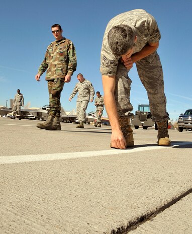 NELLIS AIR FORCE BASE, Nev. -- Senior Airman Jonathan Woodward, Shaw AFB, S.C., checks the ground for foreign object debris Feb. 25 on the Red Flag flight line. Airman Woodward is an egress technician participating in his second Red Flag exercise. (U.S. Air Force photo by Tech. Sgt. Chris Flahive)