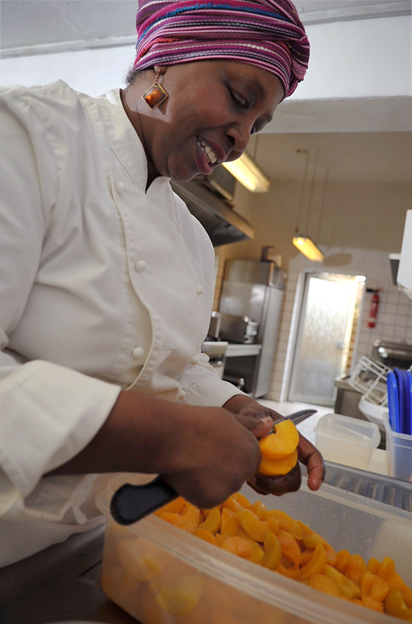 Brenda 'Mama' West, professional chef, prepares peaches to be baked into a peach cobbler in the kitchen of her restaurant, Ramstein village, Germany, Feb. 25, 2010. Mama West has been volunteering her time and cooking skills to feed U.S. servicemembers and wounded warriors in the KMC for over a decade. (U.S. Air Force photo by Senior Airman Tony R. Ritter) 
 
