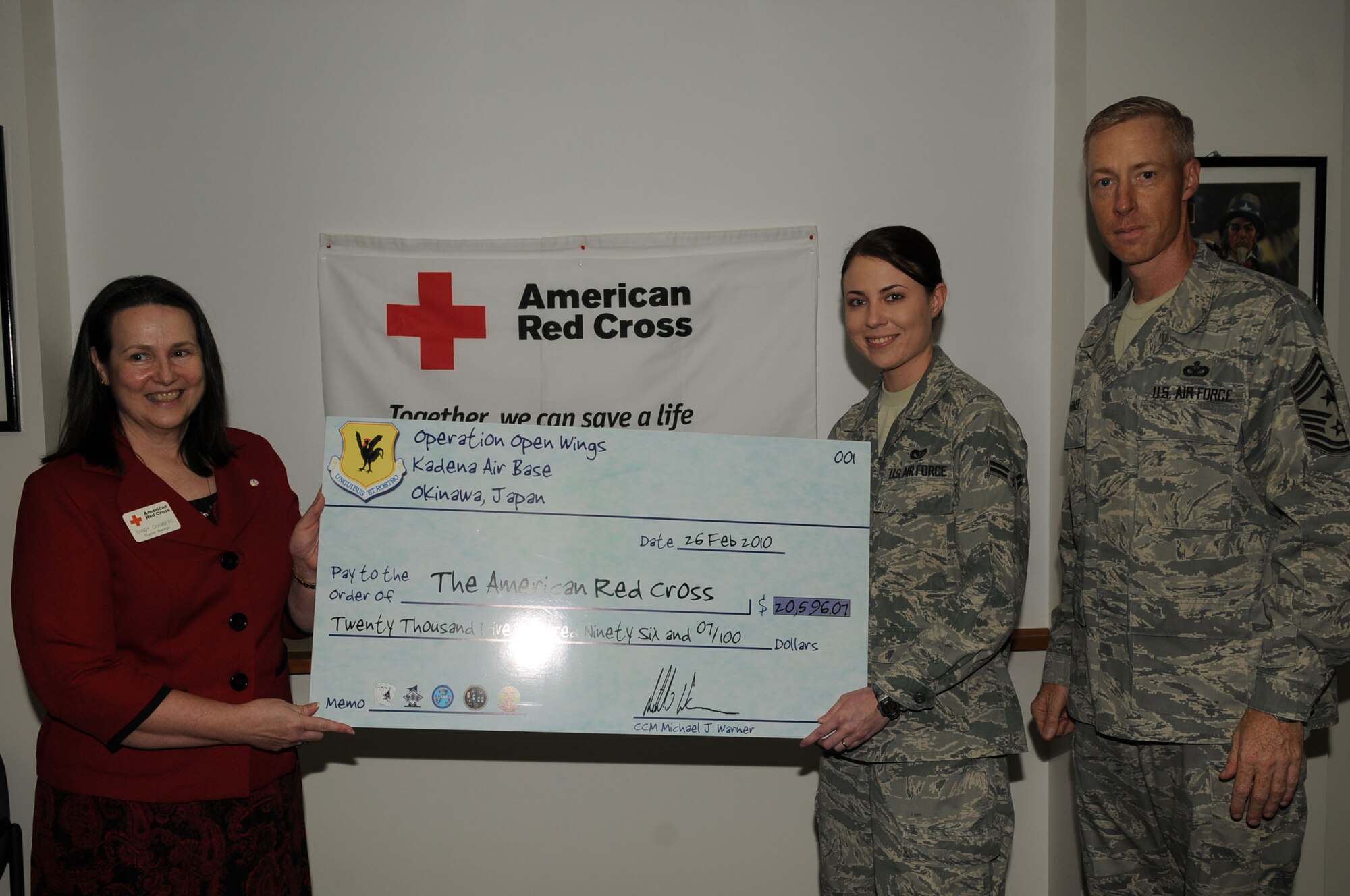 Chief Master Sgt. Michael Warner, 18th Wing command chief master sergeant, Airman 1st Class Jennifer Crouse, 18th Civil Engineer Squadron, present Mrs. Sandy Chambers, Kadena Red Cross Station Manager, a check for $20,596.07 from Operation Open Wings at Kadena Air Base, Mar 2. Operation Open Wings held events across Kadena and had a final $6,000 donation from the 733rd Air Mobility Squadron own Operation Hai Hope. The fundraisers were in response to the humanitarian relief in Haiti. (U.S. Air Force photo / Senior Airman Amanda Grabiec) 