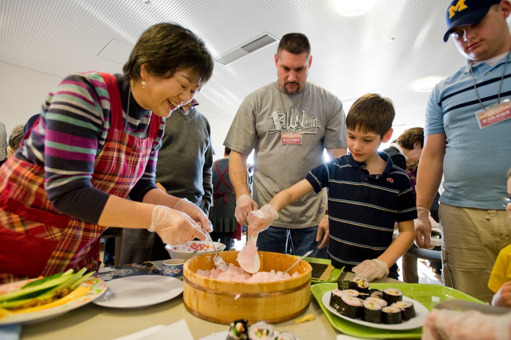 MISAWA CITY, Japan -- Yoko Baba, Misawa City resident, assists Tyler Beverly in making sushi rolls for the first time during the Japanese and American Exchange Festival Feb. 28 at the Misawa International Center. Tyler is the son of Master Sgt. Phillip Beverly, 14th Aircraft Maintenance Unit weapons-section chief. The festival included a food-tasting session featuring dishes from both countries and was followed by a musical performance starring Japanese and American children from the community. (U.S. Air Force photo/Senior Airman Jamal D. Sutter)