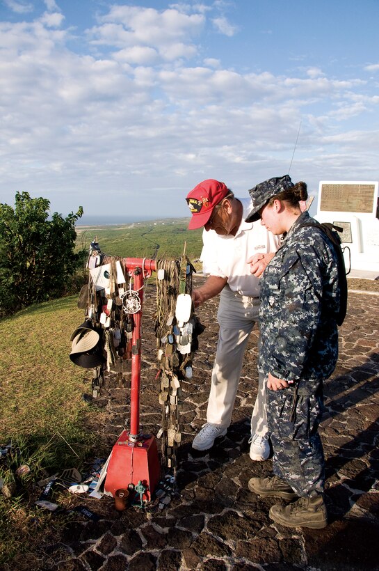 Joe Weinmayer, 83, who fought in the Battle of Iwo Jima and served in the Marine Corps from June 8, 1944, to Aug. 14, 1946, looks at dog tags placed on the Marine Corps monument on Iwo Jima as a sailor escort watches.