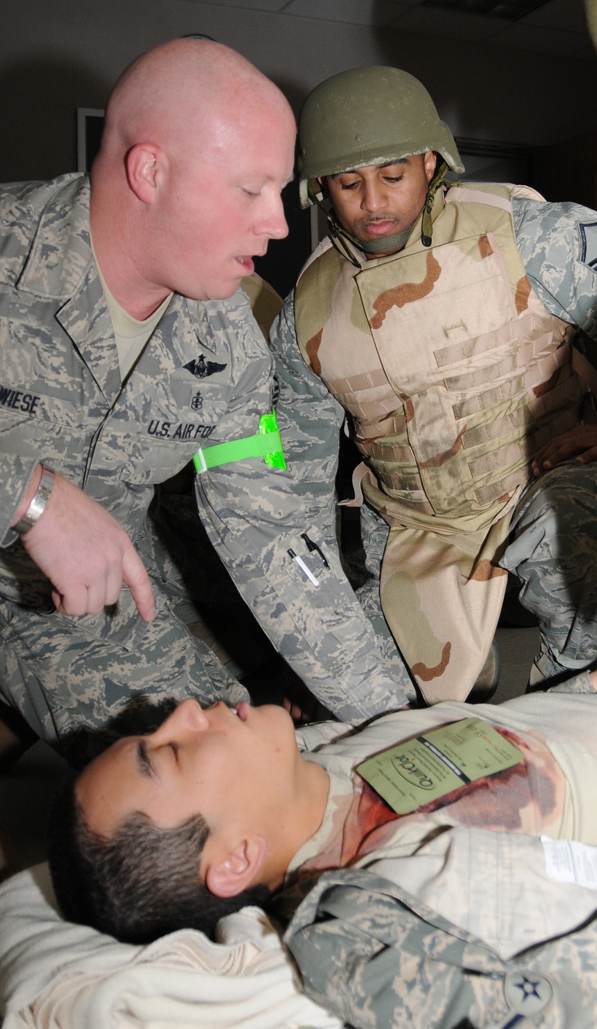 Tech. Sgt. Matthew Wiese, an exercise evaluation team member from the 81st Aerospace Medicine Squadron, discuss self aid and buddy care with Master Sgt. Jimmy Freeman, 332nd TRS, as Airman Daniel Zopf, 332nd TRS student, portrays a victim with a chest wound Feb. 25 at the CRTC.  (U.S. Air Force photo by Kemberly Groue)