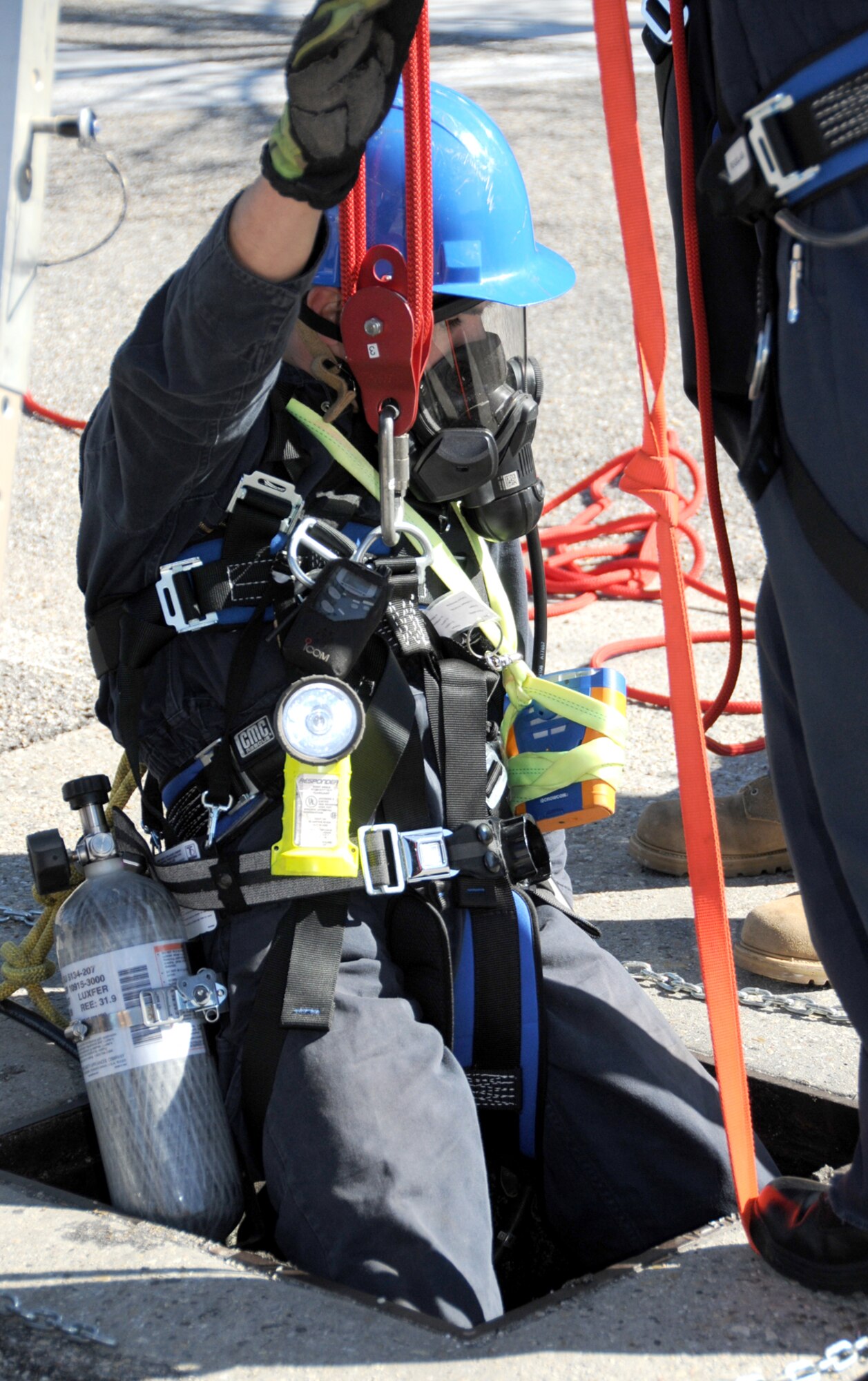 Senior Airman Mark Born, a Keesler firefighter, is lowered into a manhole in front of Wolfe Hall for confined space training Feb. 25.  (U.S. Air Force photo by Kemberly Groue)
