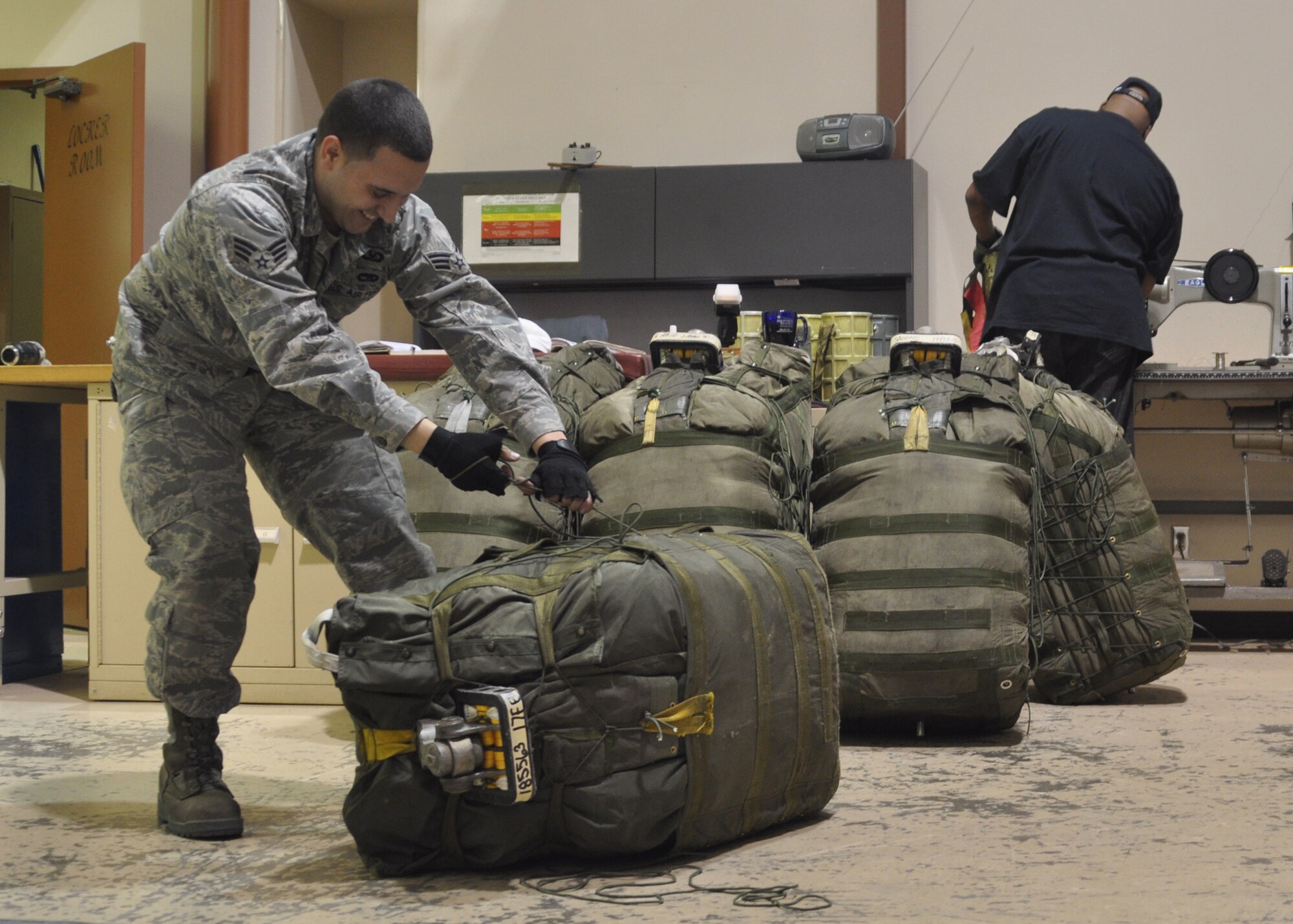 Senior Airman Xavier Medina, a Regular Air Force aircrew flight equipment journeyman attached to the 917th Wing at Barksdale Air Force Base, La., tugs at a series of strings in order to tighten and secure a B-52 Stratofortress parachute pack. Airman Medina, who is working at the 917th in support of Total Force Integration, packed the parachute while being filmed and photographed for an Air National Guard training video. (U.S. Air Force Photo/Senior Airman Crystal Marie Jordan)