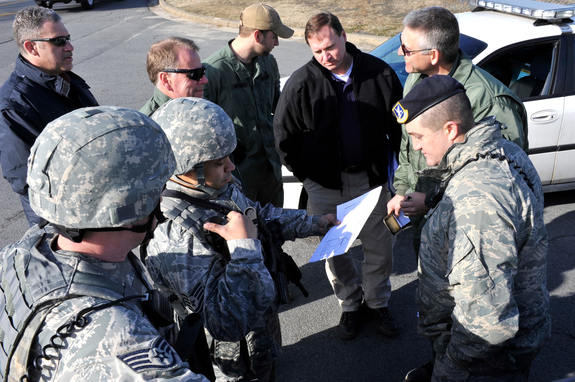 (Left) Tech. Sgt. Eric Pelican and Master Sgt. Keith Gray, 19th Security Forces Squadron patrolmen, and Federal Bureau of Investigations agents receive updates from an incident commander Feb. 26 during an exercise on base. Security forces Airmen were alerted of a simulated scenario and acted with immediate response. (U.S. Air Force photo by Christine Clark)