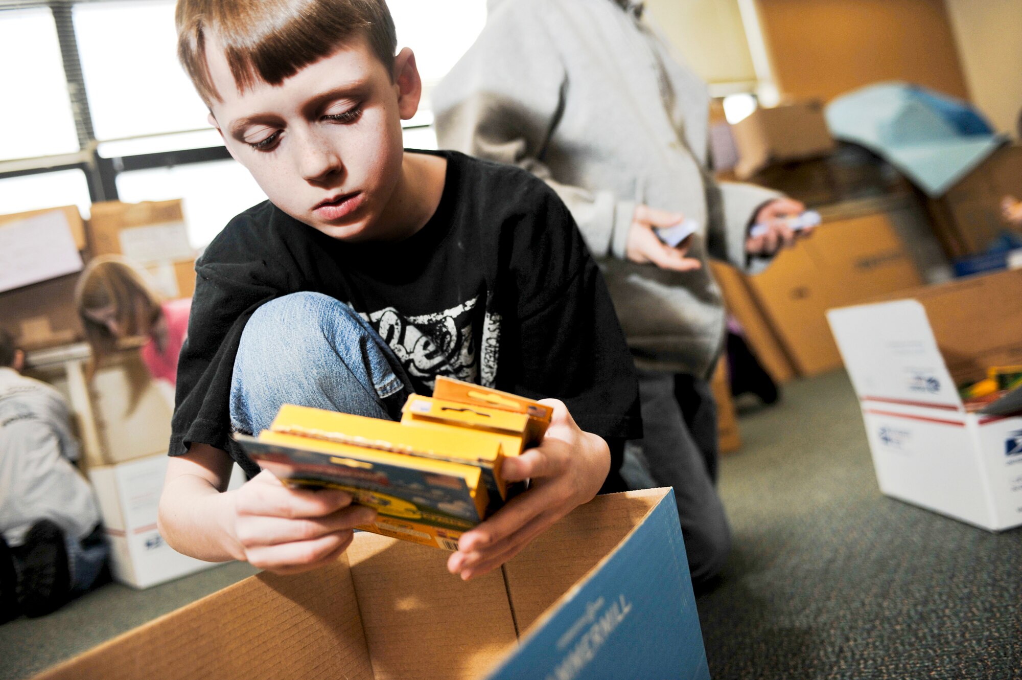 Michael Diller, grabs several boxes of markers to pack one of the boxes Feb. 25, 2010, that will be sent to students in Konar River Valley, Afghanistan. Michael is fourth-grade student at Aurora Elementary School at Elmendorf Air Force Base, Alaska. (U.S Air Force photo/Airman 1st Class Christopher Gross)