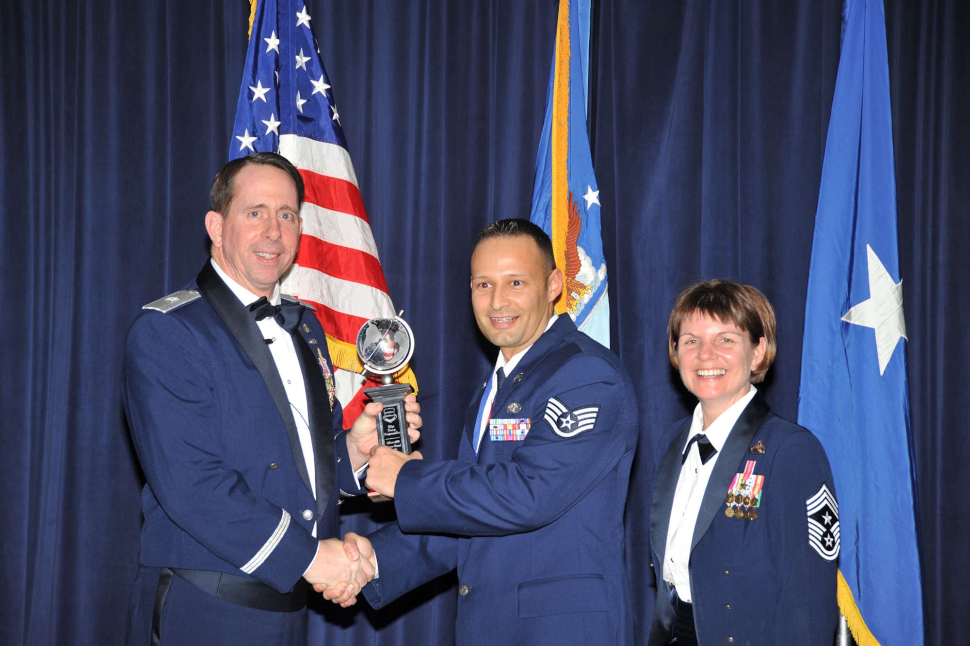 OFFUTT AIR FORCE BASE, Neb. - Brig. Gen. John N.T. Shanahan, 55th Wing commander, presents Staff Sgt. Henry Geigenmiller, 55th Wing, the Honor Guard Non-commissioned Officer of the Year Award at the 55th Wing Annual Awards Banquet at the Patriot Club here Feb. 26, as Chief Master Sgt. Lisa Sirois, 55th Wing command chief, looks on. U.S. Air Force photo by D.P. Heard