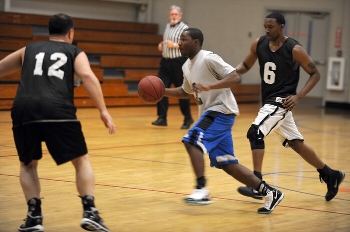 Robert Degregorio, left, and Fernando Whitten, right, guard Douglas Adams during the intramural basketball game held at the Fitness and Sports Center March 2, 2010, at Joint Base Charleston, S.C. The 628th Logistics Readiness Squadron defeated the 437th Operations Support Squadron 45-37, which brought their winning streak to 4-0 for the season so far. Degregorio and Whitten are both with the 628 LRS and Adams is with the 437 OSS.(U.S. Air Force photo/Staff Sgt. Marie Brown)