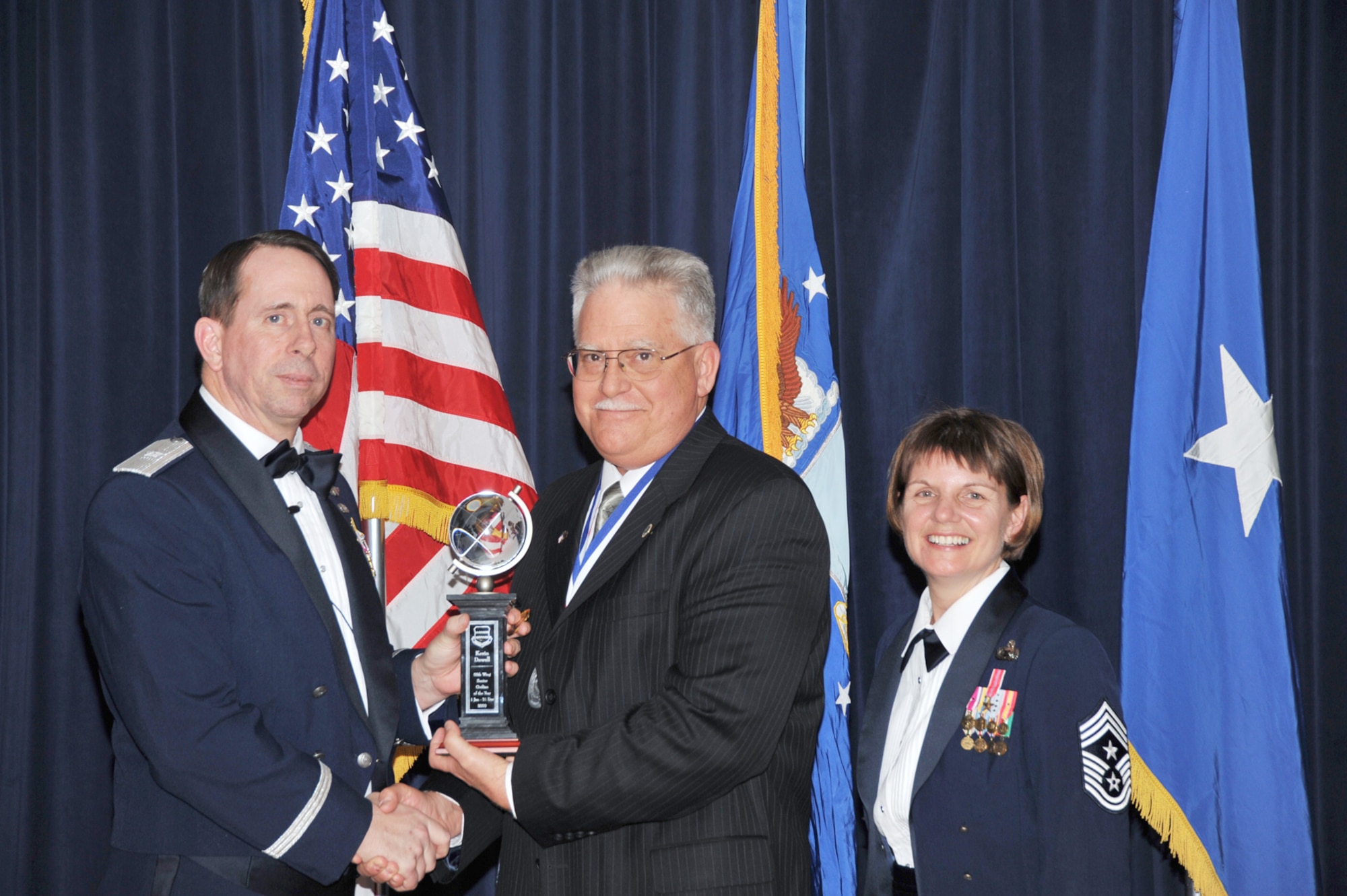 OFFUTT AIR FORCE BASE, Neb. - Brig. Gen. John N.T. Shanahan, 55th Wing commander, presents Kevin Dowell, 55th wing, the Senior Civilian of the Year Award Feb. 26 at the 55th Wing Annual Awards Banquet at the Patriot Club here, as Chief Master Sgt. Lisa Sirois, 55th Wing command chief looks on. U.S. Air Force photo by D.P. Heard