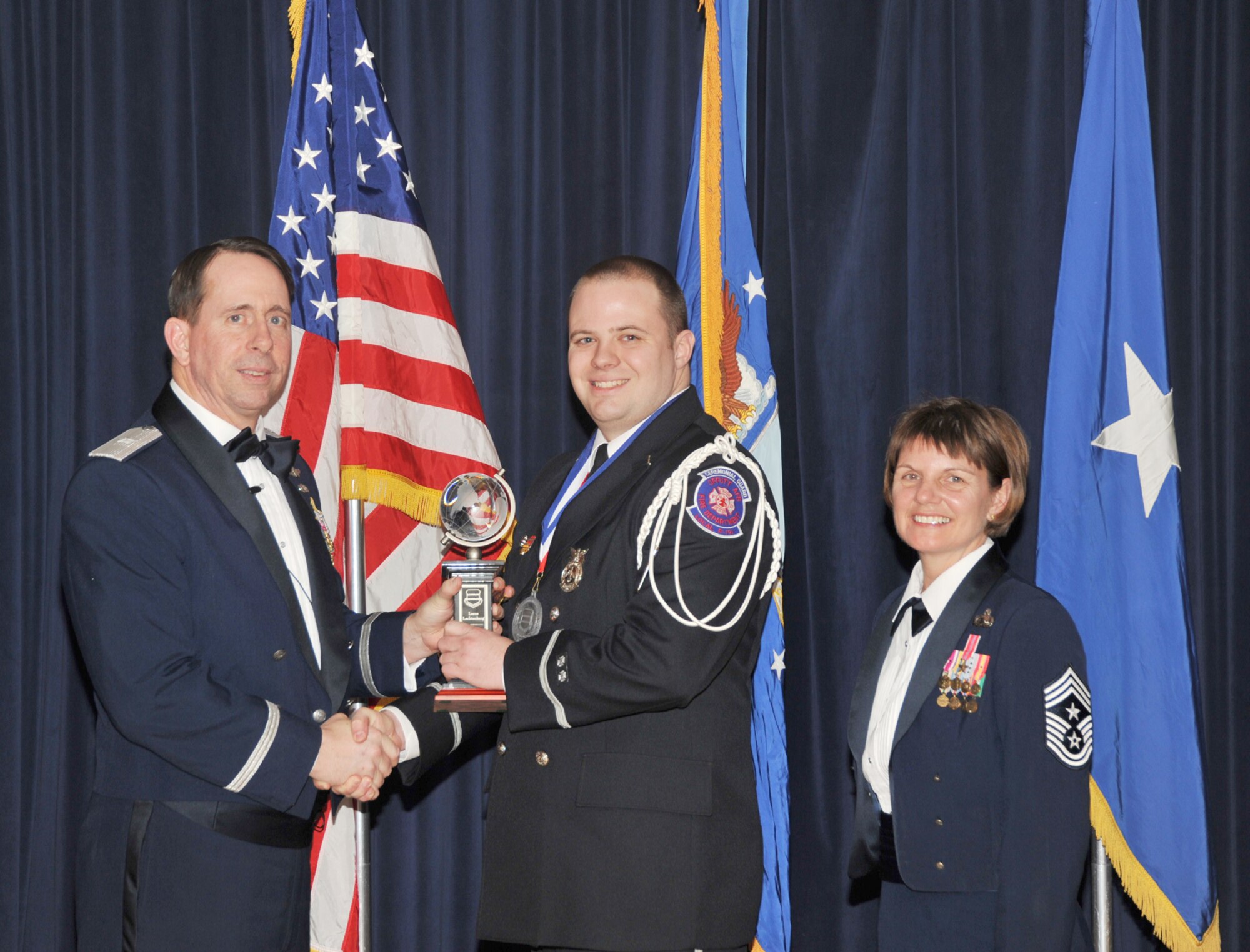 OFFUTT AIR FORCE BASE, Neb. - Brig. Gen. John N.T. Shanahan, 55th Wing commander, presents Lucas Lechtenberg, 55th Civil Engineering Squadron, the Intermediate Civilian of the Year Award Feb. 26 at the Patriot Club here during the 55th Wing Annual Awards Banquet as Chief Master Sgt. Lisa Sirois, 55th Wing command chief looks on. U.S. Air Force photo by D.P. Heard