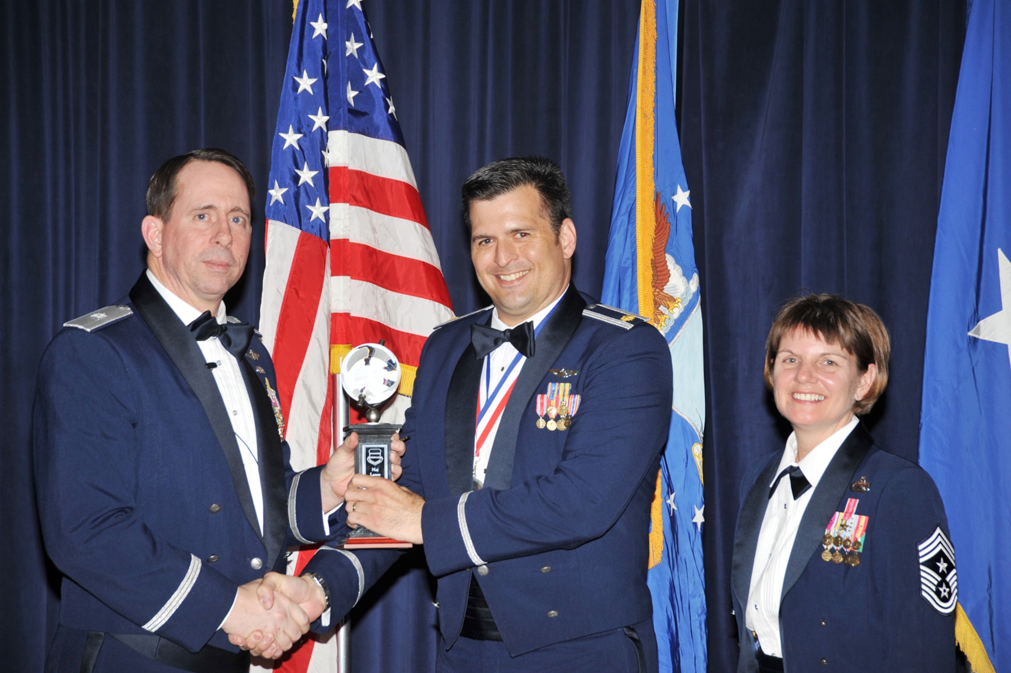 OFFUTT AIR FORCE BASE, Neb. - Brig. Gen. John N.T. Shanahan, 55th Wing commander, presents Maj. Lance Benson, 43rd Electronic Combat Squadron, the Field Grade Officer of the Year Award at the Patriot Club here Feb. 26 during the 55th Wing Annual Awards Banquet as Chief Master Sgt. Lisa Sirois, 55th Wing command chief looks on. U.S. Air Force photo by D.P. Heard