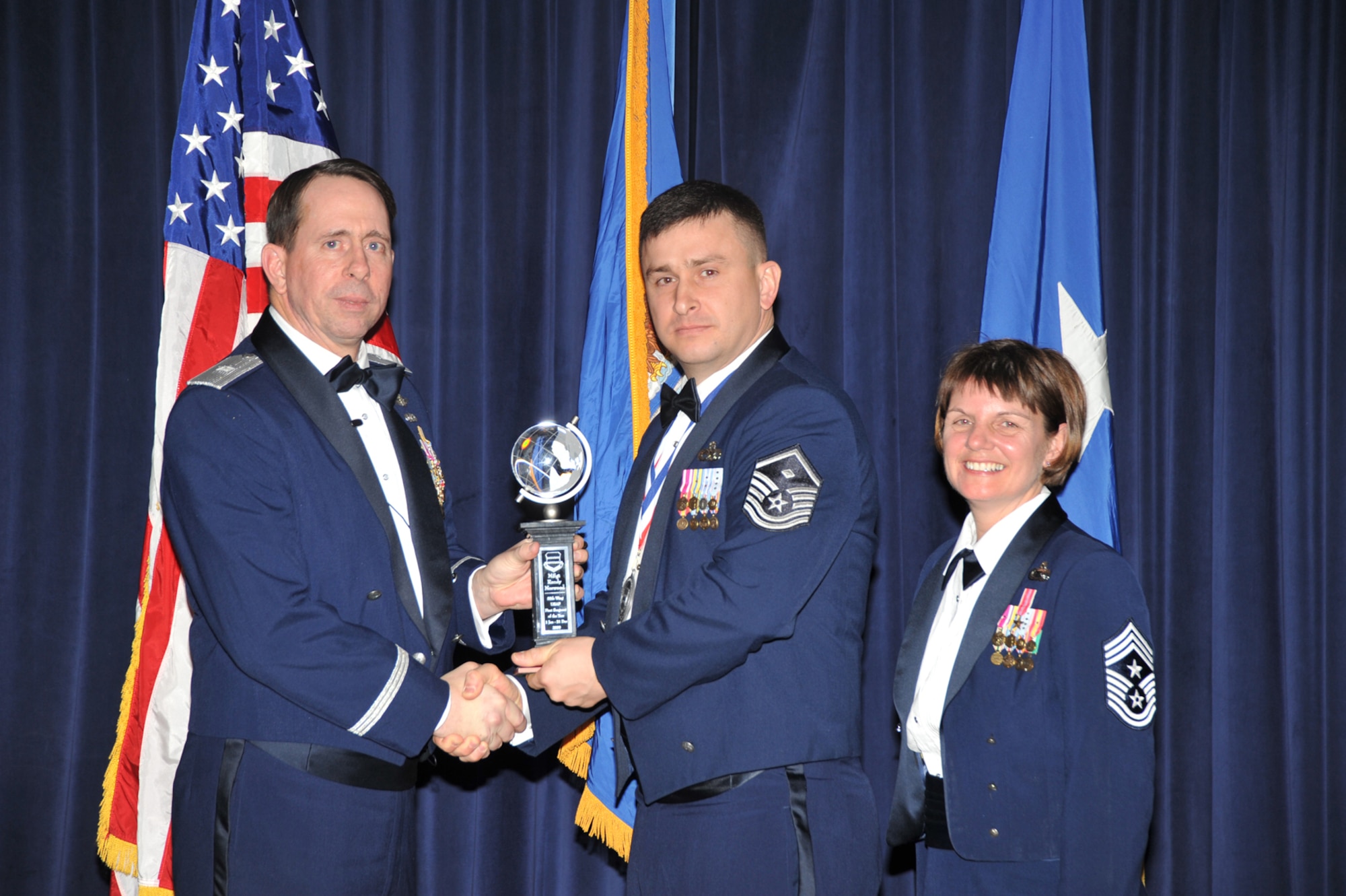 OFFUTT AIR FORCE BASE, Neb. - Brig. Gen. John N.T. Shanahan, 55th Wing commander, presents Master Sgt. Randy Norwood, 55th Force Support Squadron, the First Sergeant of the Year Award at the 55th Wing Annual Awards Banquet Feb. 26 at the Patriot Club here, as Chief Master Sgt. Lisa Sirois, 55th Wing command chief looks on. U.S. Air Force photo by D.P. Heard