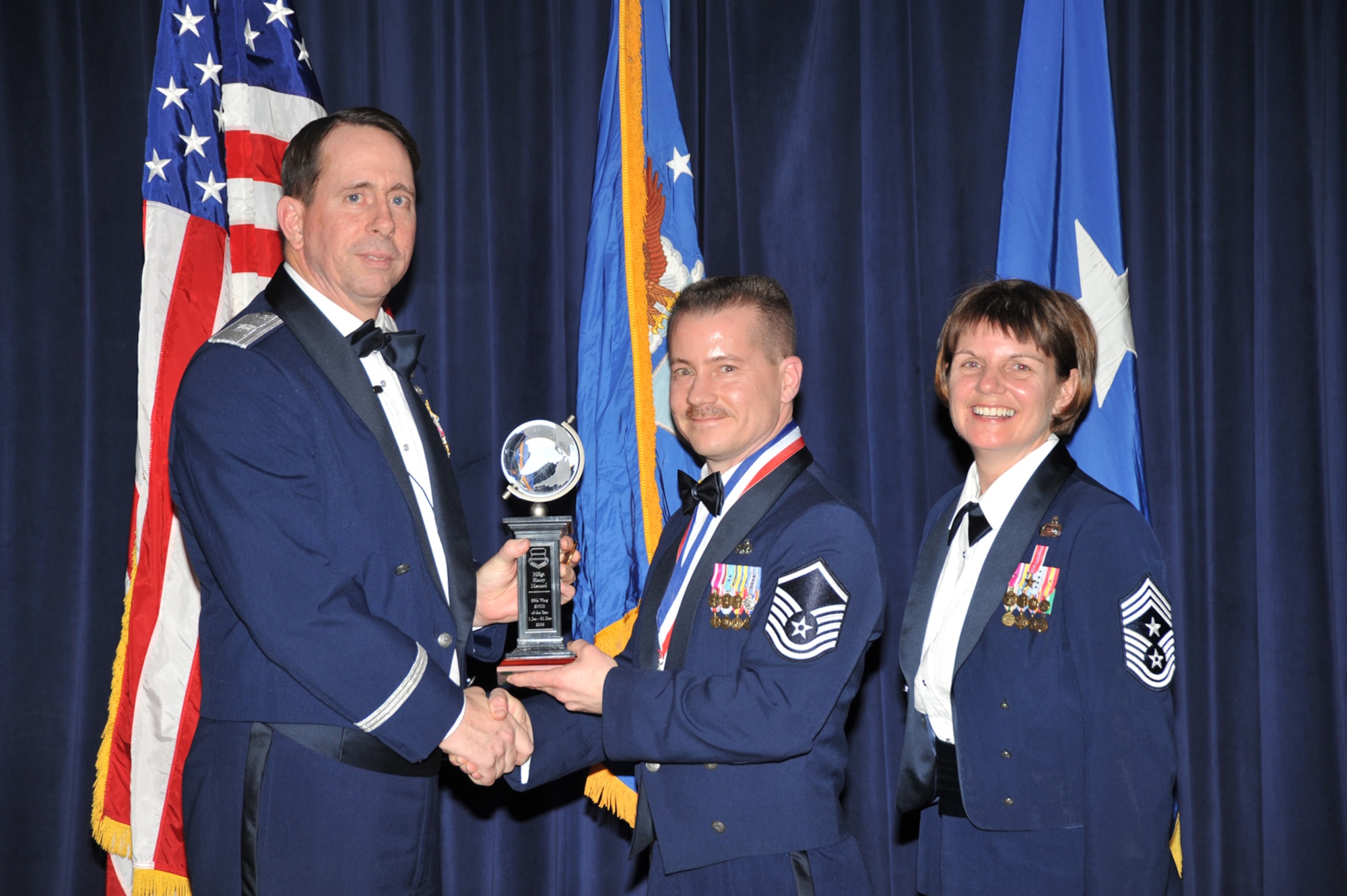 OFFUTT AIR FORCE BASE, Neb. - Brig. Gen. John N.T. Shanahan, 55th Wing commander, presents Master Sgt. Harry Menard, 55th Aircraft Maintenance Squadron, the Senior Non-commissioned Officer of the Year Award at the 55th Wing Annual Awards Banquet Feb. 26 at the Patriot Club here as Chief Master Sgt. Lisa Sirois, 55th Wing command chief looks on. U.S. Air Force photo by D.P. Heard