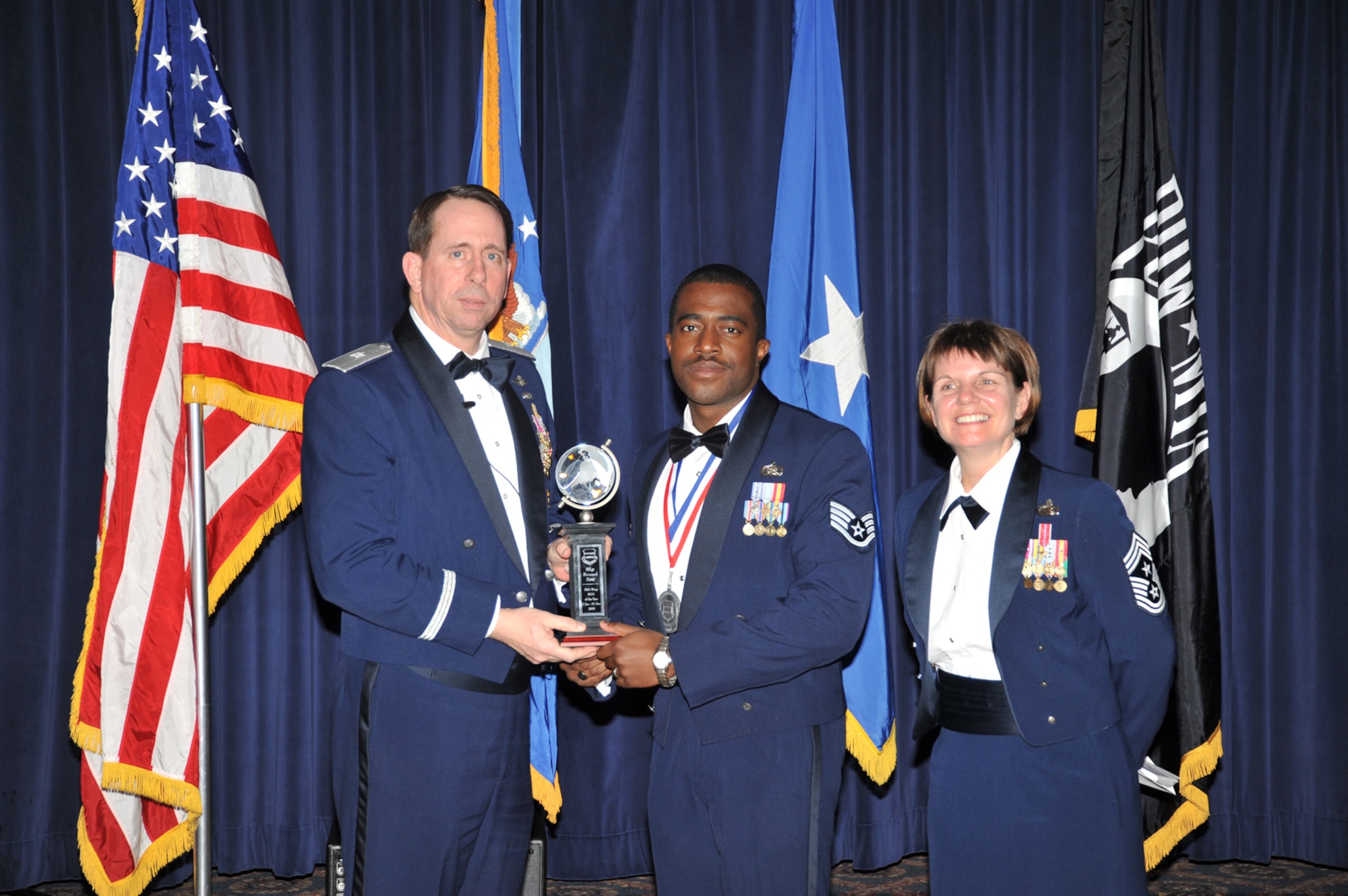OFFUTT AIR FORCE BASE, Neb. - Brig. Gen. John N.T. Shanahan, 55th Wing commander, presents Staff Sgt. Bernard Byer Jr., 390th Intelligence Squadron, the Non-commissioned Officer of the Year Award at the 55th Wing Annual Awards Banquet Feb. 26 at the Patriot Club here, as Chief Master Sgt. Lisa Sirois, 55th Wing command chief looks on. U.S. Air Force photo by D.P. Heard