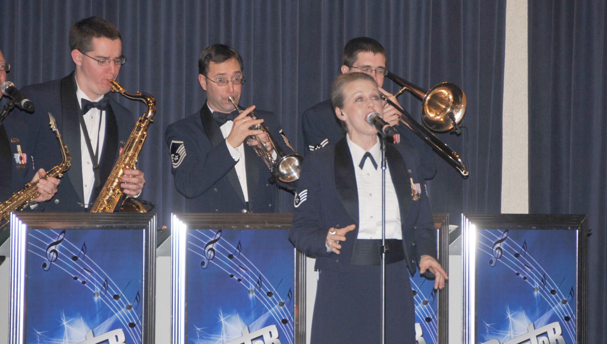 OFFUTT AIR FORCE BASE, Neb. - Staff Sgt. Krista Joyce, a singer with the Heartland of America Band's ensemble "Raptor," sings while the group's brass section performs behind her during a performance Feb. 26 at the 55th Wing Annual Awards Banquet at the Patriot Club here. U.S. Air Force photo by D.P. Heard