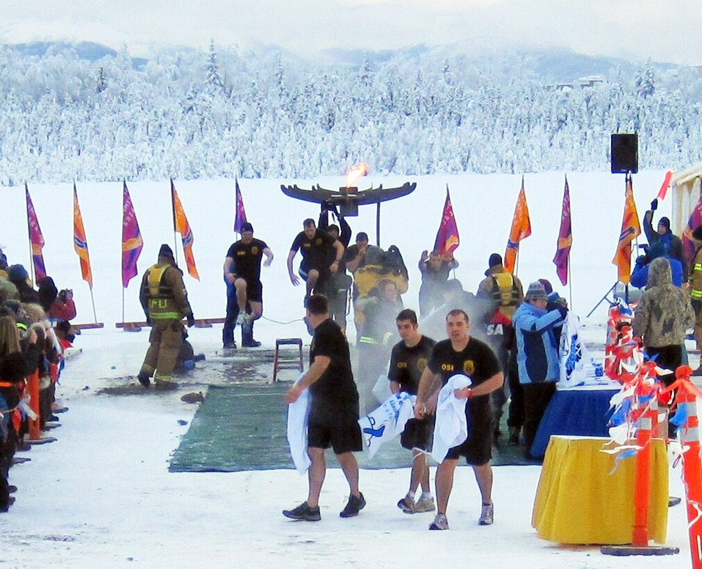 The Frosty Fuzz team, made up of members of the Air Force Office of Special Investigations, Detachment 631, walk away from their dive into Goose Lake. Though the temperature hovered around zero degrees, hundreds of jumpers weren't deterred from taking the plunge into icy Goose Lake. The event raised funds for Special Olympics Alaska. Pictured in the foreground are are (l to r) Special Agent Mike Charland, Matt Charland and Special Agent Nick Murphy. Pictured in the background, taking positions for the plunge are (l to r) Special Agents Keith King, John Wisocky,  Shaun Cassidy and Travis Williamson. (U.S. Air Force photo)