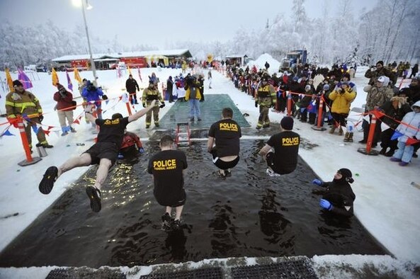 The Frosty Fuzz team, made up of members of the Air Force Office of Special Investigations, Detachment 631, dive into Goose Lake. Though the temperature hovered around zero degrees, hundreds of jumpers weren't deterred from taking the plunge into icy Goose Lake. The event raised funds for Special Olympics Alaska. Pictured are (l to r) Special Agents Travis Williamson, Shaun Cassidy,  John Wisocky and Keith King. (Courtesy photo/Marc Lester, Anchorage Daily News)