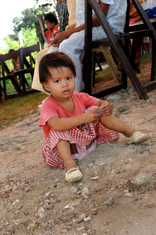 A young girl plays in the dirt as she and her mother wait for care at a medical outreach event in Lamitan, Philippines, Feb. 25, 2010.