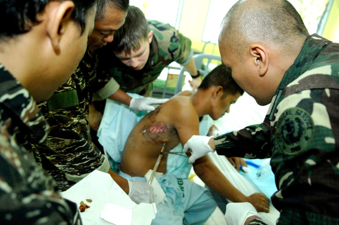 Philippine navy special operation troops clean the wound and change bandages of a recently wounded Philippine soldier Feb. 24, 2010, at Camp Navarro General Hospital near Zamboanga, Philippines. The team of troops visit the hospital daily to assist and learn medical care as part of an advance combat medical training course taught by U.S. Navy Seals.