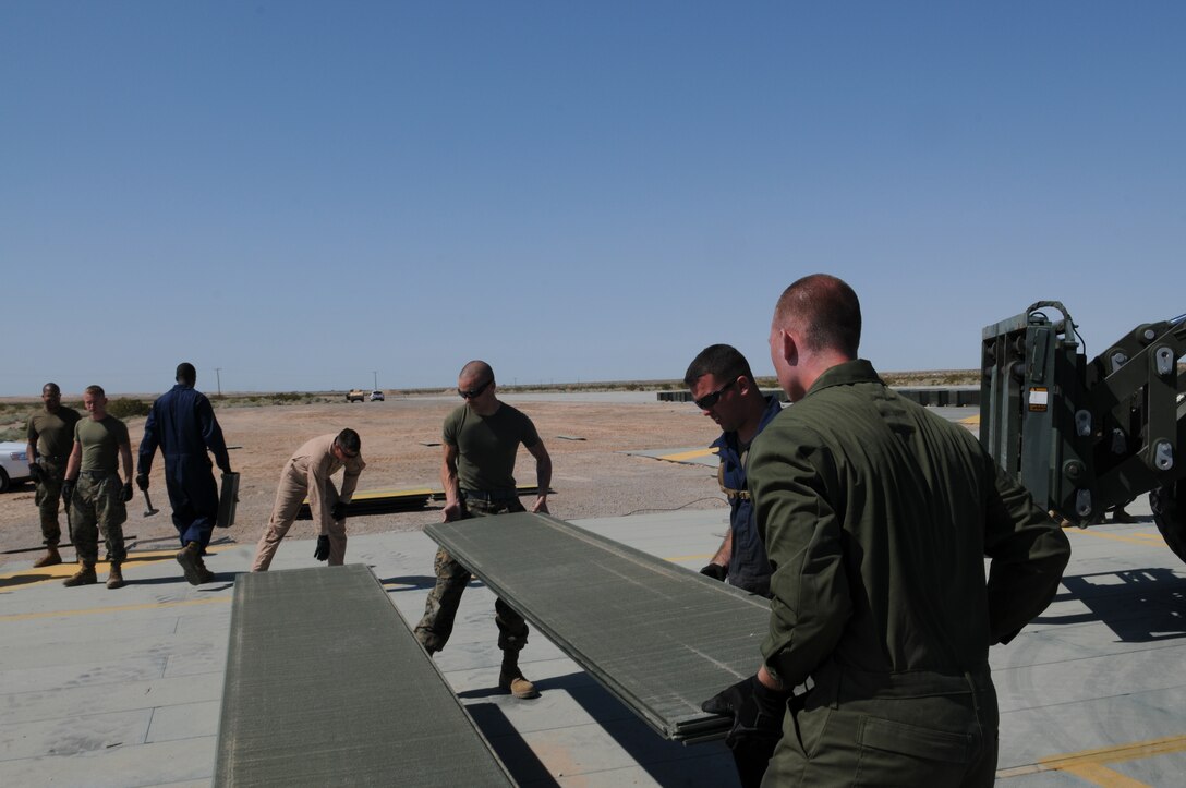 Marine Wing Support Squadron 371 Marines lift a 110-pound mat at Auxiliary Airfield 2 March 3, 2010. Work on AUX-2 began March 1 and is scheduled for completion by the end of the month. The squadron began replacing matting in March to certify the airfield, which simulates the deck of a carrier ship, for another year of carrier landing training by aviation units. MWSS-371 is based at the Marine Corps Air Station in Yuma, Ariz. The auxiliary airfield is located on the Barry M. Goldwater Range east of the station.