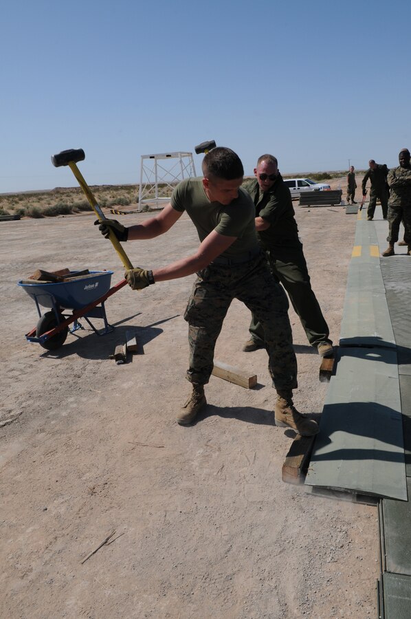 Marine Wing Support Squadron 371 Marines pound an H-connecting-mat into place at Auxiliary Airfield 2 March 3, 2010. The airfield’s taxiway and maintenance pad were replaced as part of the airfields annual recertification.  The recertification will allow the airfield, which simulates the deck of a carrier ship, to function for another year as a place where aviation units can carry out carrier landing training. MWSS-371 is based at the Marine Corps Air Station in Yuma, Ariz. The auxiliary airfield is located on the Barry M. Goldwater Range east of the station.