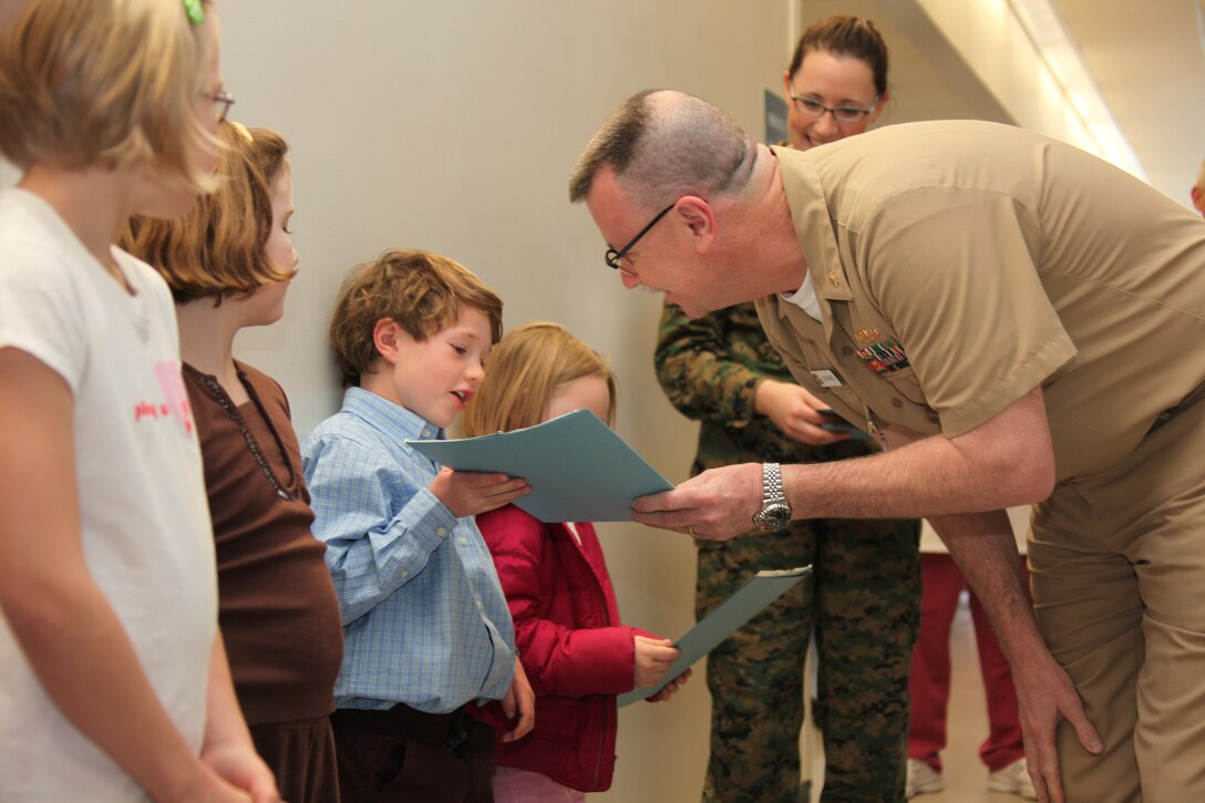 Capt. William Leonard, Cherry Point’s Naval Health Clinic’s executive officer, presents Owen Black his award during the coloring contest award ceremony at the 12th dental clinic, March 4. The six children received awards for winning Cherry Points’ Children’s Dental Health Month coloring contest.