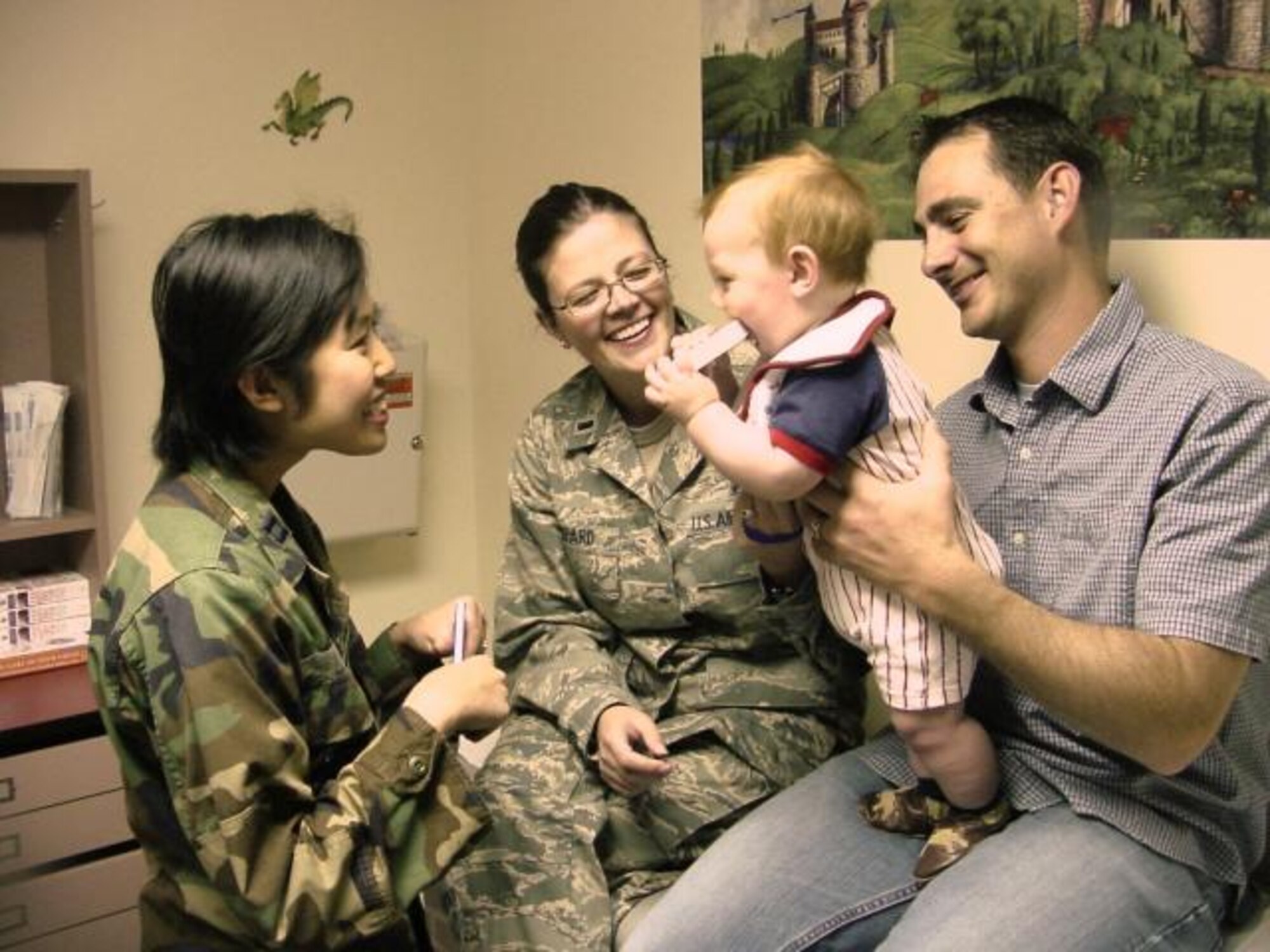 Air Force Capt. (Dr.) Minh-Thu Le interacts with her patient, 8-month-old Alexander, as he performs the common newborn ritual of "mouthing the book." Parents, Air Force 1st Lt. Alice L. Shepard and her husband, Steven, happily look on at Travis Air Force Base in California. (USAF photo / James Spellman, Jr.)