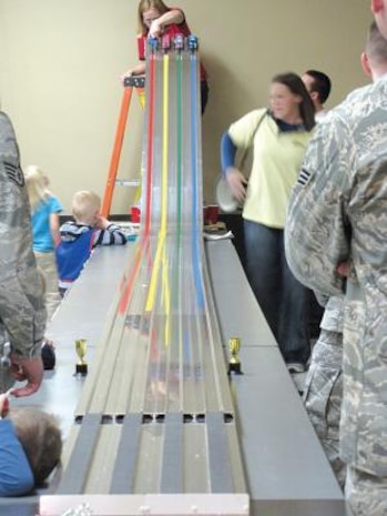 Debby Riggs, Hill Air Force Base Awana Sparks director, releases four race cars down the sloped track.