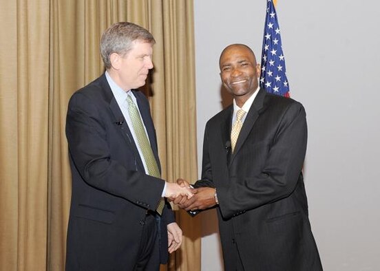 Mark Johnson, Ogden Air Logistics Center executive director, honors Salome Thomas-EL at the Transformation Symposium by giving him a special installation Air Force coin in accordance with military custom and tradition.