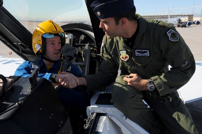 Members of the Navy’s Flight Demonstration Squadron, the Blue Angels, traded in their blue and gold F/A-18 Hornets to strap into an U.S. Air Force red, white and blue Thunderbird F-16 Fighting Falcon here, today
