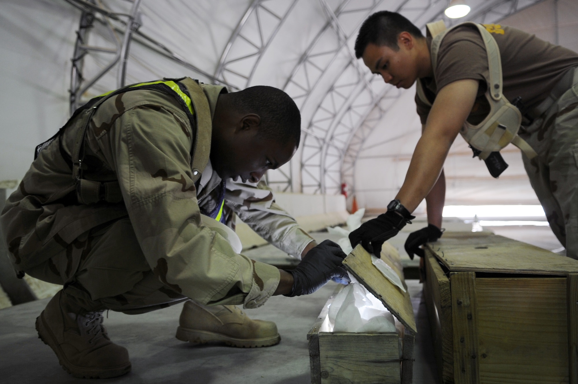 Petty Officers 2nd Class Wesley Ferrell and Jason Calugcugan inspect cargo for contraband and agriculture before it is shipped out of the area of responsibility at Joint Base Balad, Iraq, Feb. 27, 2010.  Both are customs border clearance agents with the Naval Expeditionary Logistics Support Group Delta Company.  CBCA’s are trained in the use of weapons, driving tactical vehicles, first aid, small unit tactics, and the procedures and standards required of items and personnel re-entering the United States from overseas. (U.S. Air Force photo/Senior Airman Brittany Y. Bateman/Released)