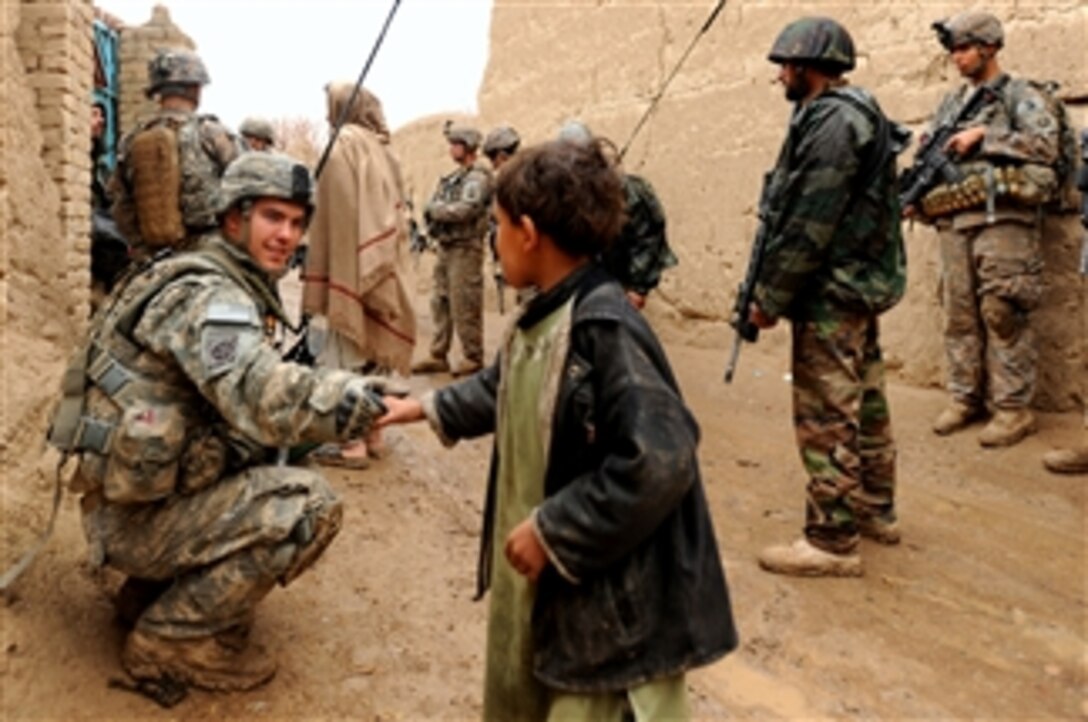 A U.S. Army soldier assigned to Charlie Company, 82nd Airborne Division shakes the hand of a young Afghan child while on a dismounted patrol at a village in southern Afghanistan on Feb. 5, 2010.  The U.S. Army and Canadian Forces Land Force Command are helping the Afghan National Army clear several villages of improvised explosive devices, weapons caches and illegal drugs.  