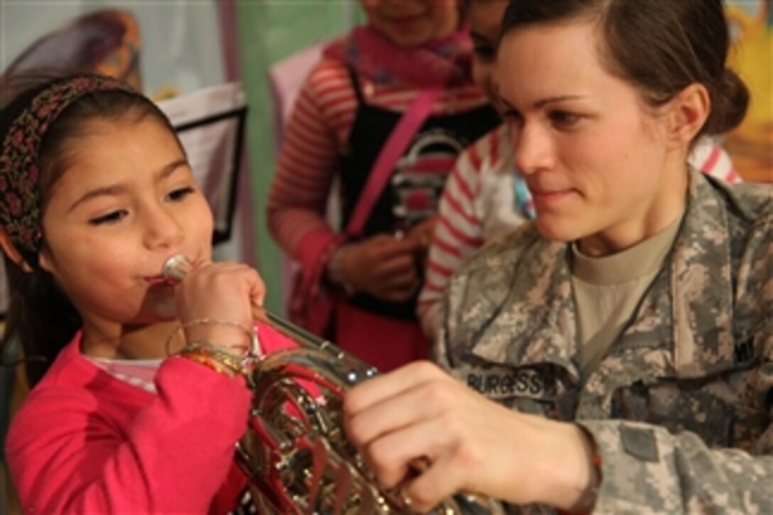 U.S. Army Sgt. Emily Burgess (right), of 1st Infantry Division, Cantigy Brass Band, teaches an Iraqi girl how to play the French horn at an Arts Festival in Kut, Iraq, on Feb. 26, 2010.  The festival consisted of Iraqi stage art, paintings and photography.  