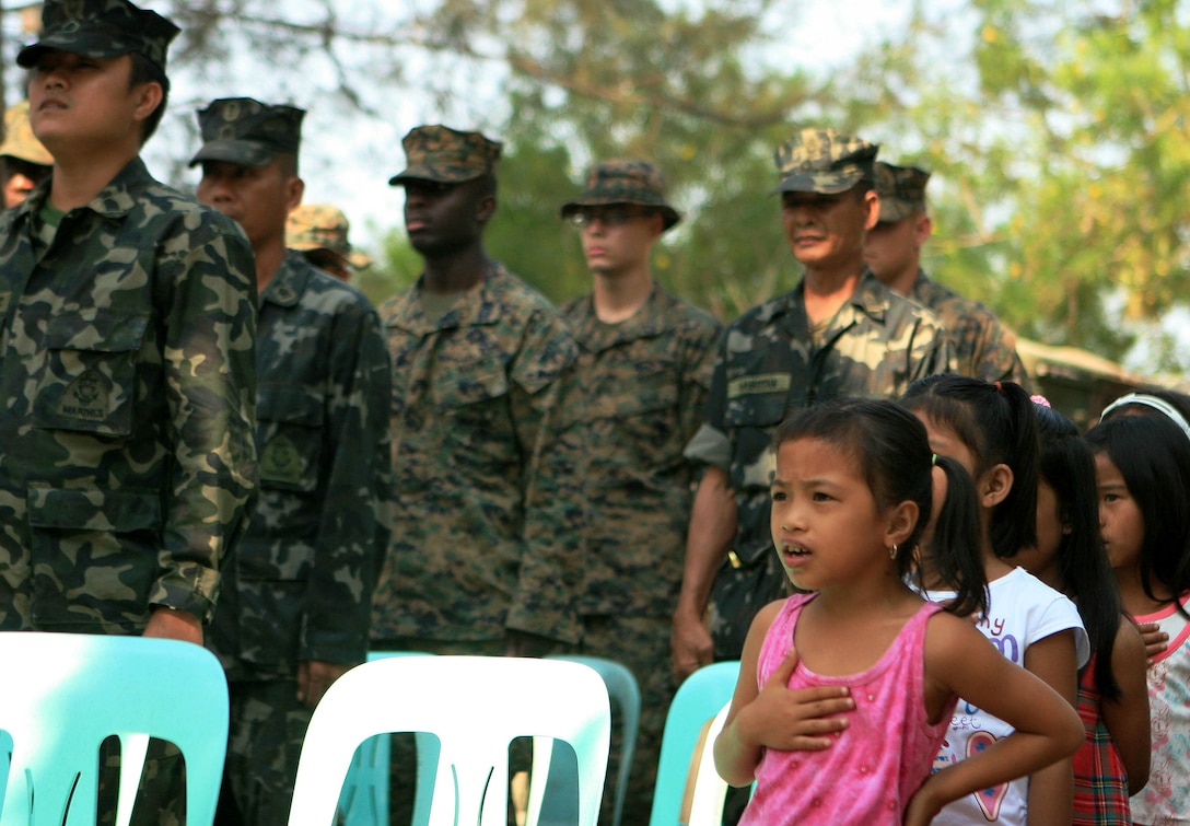 Marnay Primary School students sing the Philippine National Anthem alongside service members of the Republic of the Philippines and 31st Marine Expeditionary Unit (MEU) during an opening ceremony for an engineering civil affairs project (ENCAP), March 5. Marines and sailors with CLB-31 are rebuilding a two-room classroom at Marnay Primary School during exercise Balikatan 2010 (BK ’10). Armed Forces of the Philippines (AFP) and the U.S. are working together during BK ’10 to hone their civil-military interoperability skills to ensure more responsive, efficient and effective relief efforts. (Official Marine Corps photo by Lance Cpl. Dengrier M. Baez)