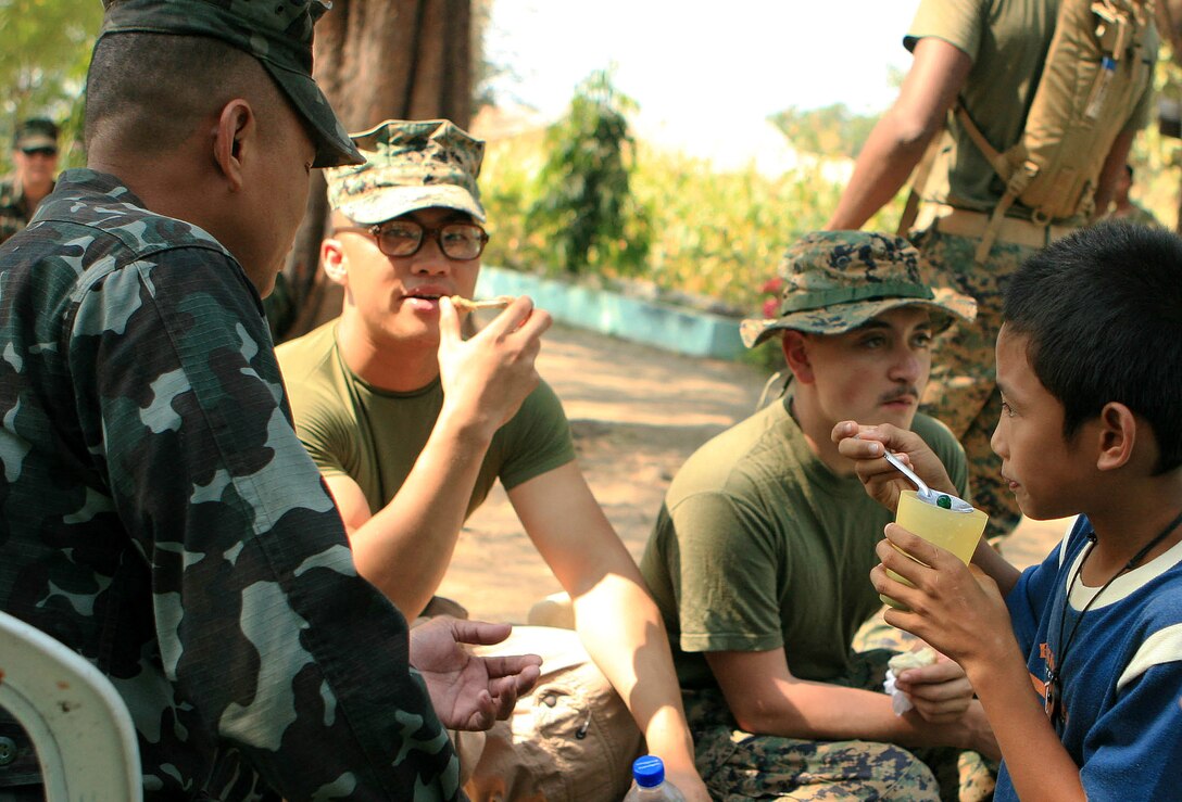 Local children sit down and enjoy a snack with a service member from the Armed Forces of the Philippines (AFP) and Marines and sailors from Combat Logistic Battalion 31 (CLB-31), 31st Marine Expeditionary Unit (MEU), after an opening ceremony for an engineering civil affairs project (ENCAP), here, March 5. Marines and sailors with CLB-31 are rebuilding a two-room classroom at Marnay Primary School during exercise Balikatan 2010 (BK ’10). Armed Forces of the Philippines (AFP) and the U.S. are working together during BK ’10 to hone their civil-military interoperability skills to ensure more responsive, efficient and effective relief efforts. (Official Marine Corps photo by Lance Cpl. Dengrier M. Baez)