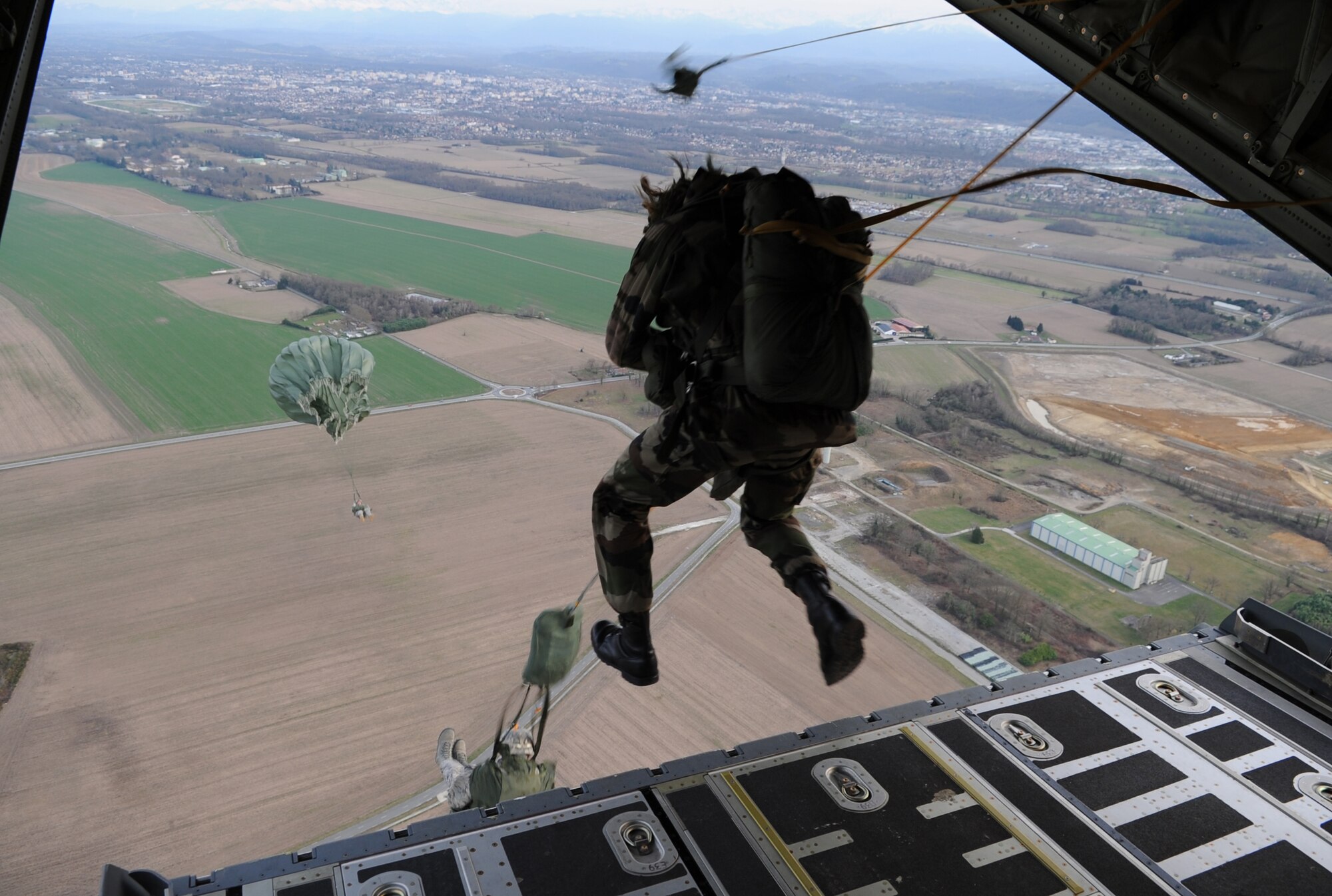 Airborne members from the 435th Contingency Response Group, 5th Quartermaster Company and the French Airborne jump from a C-130J Super Hercules at École des troupes aéroportées (ETAP) Pau, France, March 2, 2010. Members of the 435th Contingency Response Group and the 5th Quartermaster Company joined with their French military counterparts for a week of training at the École des troupes aéroportées (ETAP), or School of Airborne Troops, a military school dedicated to training the military paratroopers  the French army, located in the town of Pau, in the département of Pyrénées-Atlantiques, France.  The ETAP is responsible for training paratroopers, and for international cooperation and promotion of paratroop culture. (U.S. Air Force photo by Airman 1st Class Caleb Pierce)