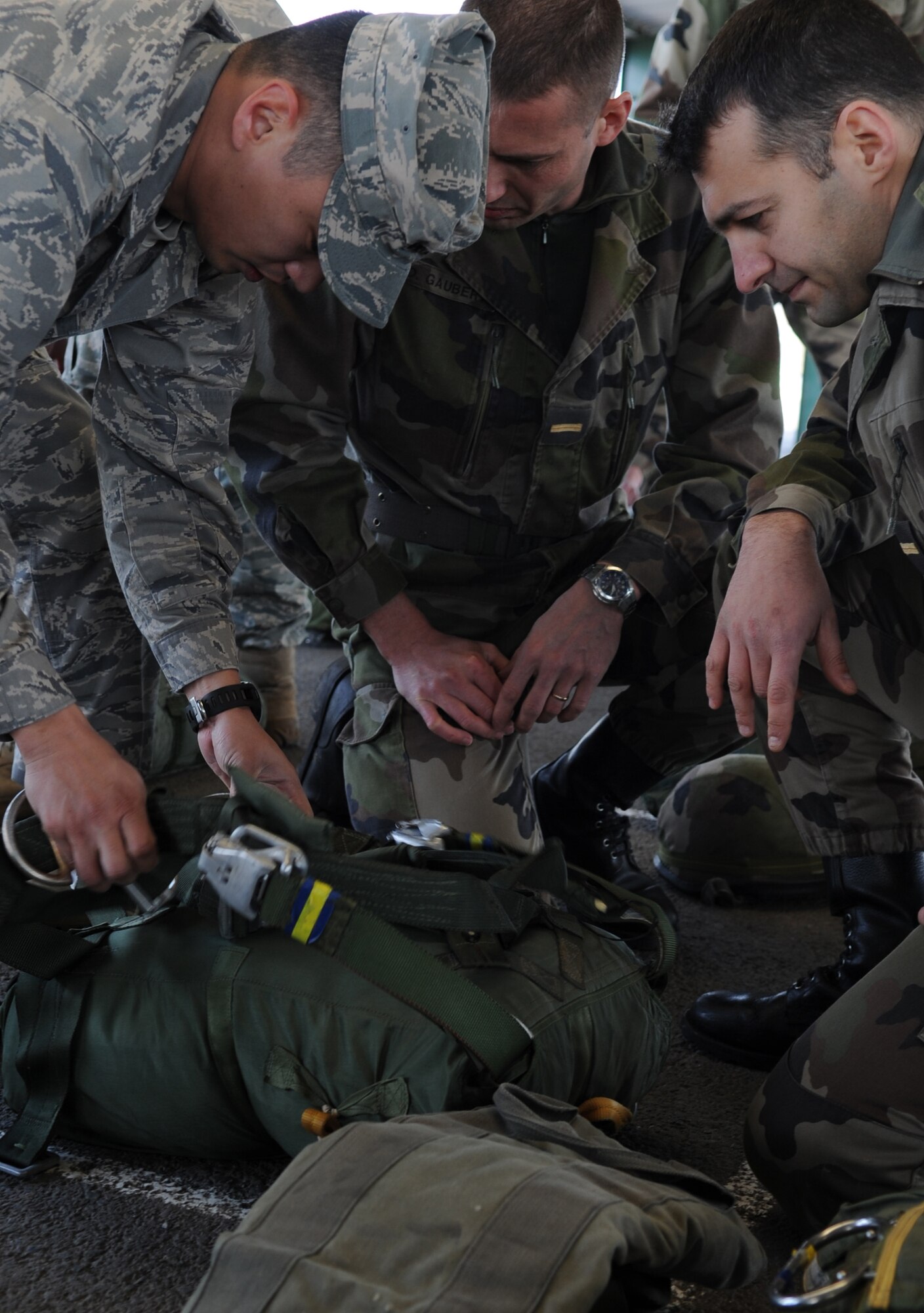 U.S. Air Force Capt. Walter Grey, 435th Air Mobility Squadron airfield operations and flight officer, helps French Airborne members ready their chute prior to a static jump from a C-130J Super Hercules at École des troupes aéroportées (ETAP) Pau, France, March 1, 2010. Members of the 435th Contingency Response Group and the 5th Quartermaster Company joined with their French military counterparts for a week of training at the École des troupes aéroportées (ETAP), or School of Airborne Troops, a military school dedicated to training the military paratroopers  the French army, located in the town of Pau, in the département of Pyrénées-Atlantiques, France. The ETAP is responsible for training paratroopers, and for international cooperation and promotion of paratroop culture. (U.S. Air Force photo by Airman 1st Class Caleb Pierce)