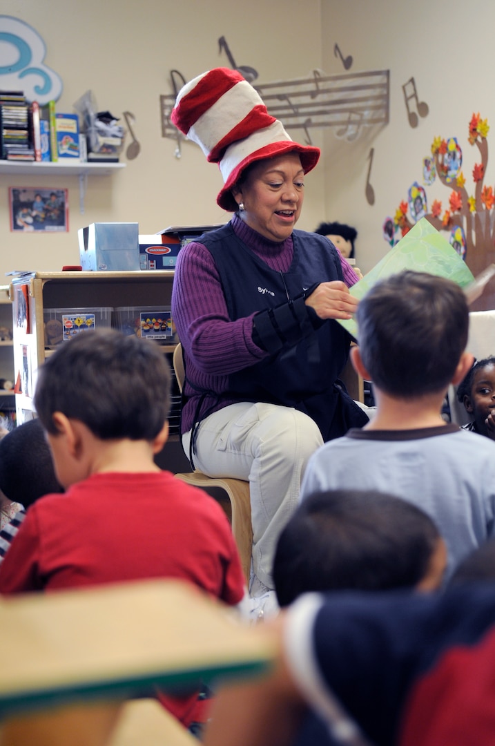 Sylvia Munoz, a Randolph Air Force Base Child Development Center care giver, celebrates Dr. Suess' birthday as she reads to her kids while wearing an iconic 'Cat in the Hat' hat. (U.S. Air Force Photo by Steve White)