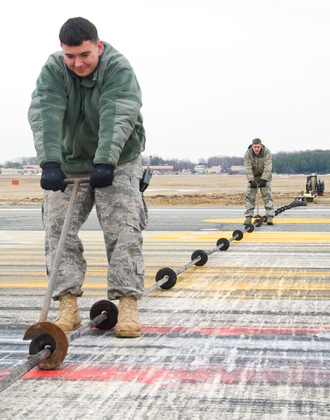 Senior Airman Jacob Henley, left, 316th Civil Engineer Squadron power production journeyman, and Airman 1st Class Casey Brown, 316 CES power production apprentice, use “doughnut pullers” to re-string and adjust the distance between doughnuts on the cable aircraft arresting system on the flightline Tuesday morning.  Similar to the arresting gear on aircraft carriers, the aircraft arresting system is also used at land-based airfields for expeditionary or emergency use to rapidly decelerate an aircraft as it lands. The systems consist of a cable laid across the aircraft landing area, which is designed to be caught by an aircraft’s tailhook. (U.S. Air Force photo/ Bobby Jones)