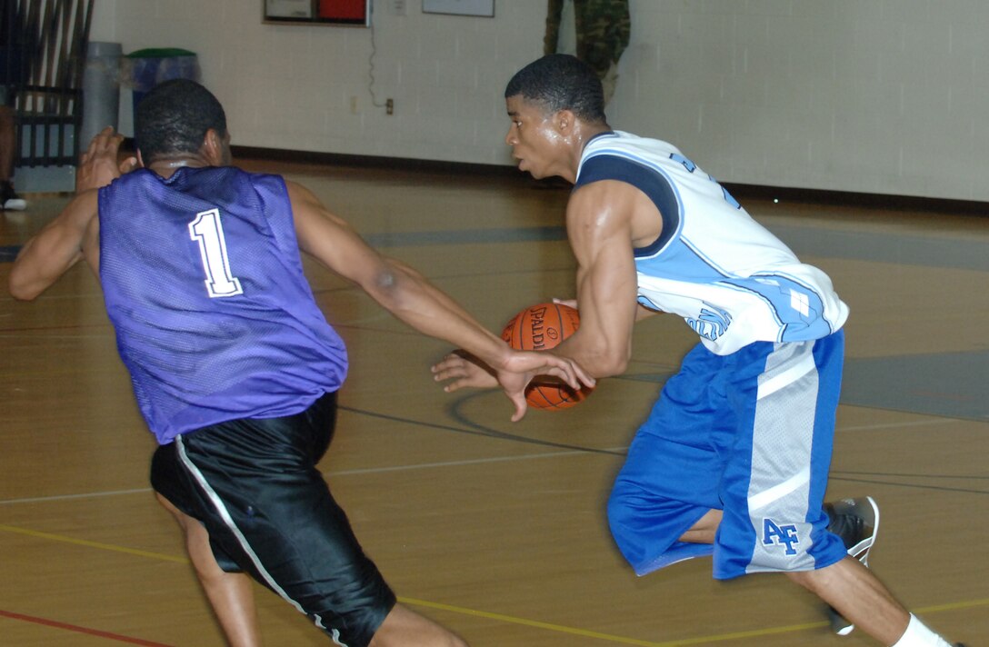 LANGLEY AIR FORCE BASE, Va. -- Air Force Targeting Center Small Forward Drew Colen drives past 1st Equipment Maintenance Squadron Guard Preston Griffin in an intramural basketball play-off game March 4 at the Shellbank Fitness Center. AFTC won the game, 65-58. (U.S. Air Force photo/Airman 1st Class Jason J. Brown)