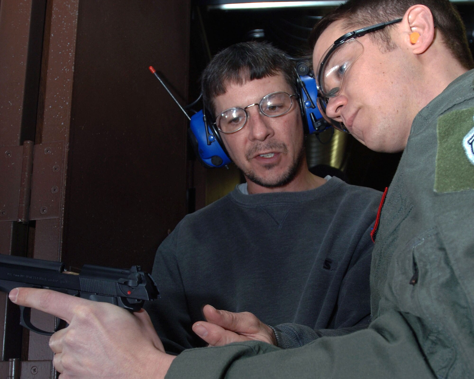 Peter Bair, 319th Security Force Squadron combat arms instructor, assists Capt. Kevin Dacy, 319th Operations Support Squadron, with clearing his M-9 pistol March 2 at the Grand Forks Air Force Base Firing Range. (U.S. Air Force photo by Airman 1st Class Amber Price)