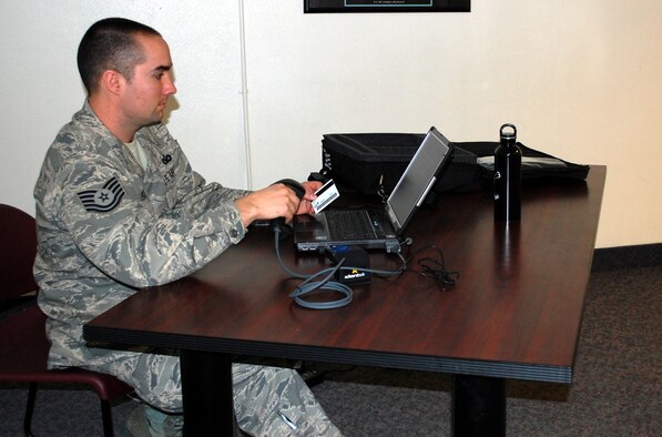 Tech. Sgt. Joseph Feigel, 341st Security Forces Squadron NCOIC, DBIDS, scans another SFS member's common access card to get him registered in the Defense Biometrics Identification System March 1. It is a requirement for all CAC and ID card holders to get registered into this new system in order to have access to Malmstrom. (U.S. Air Force photo/Valerie Mullett)