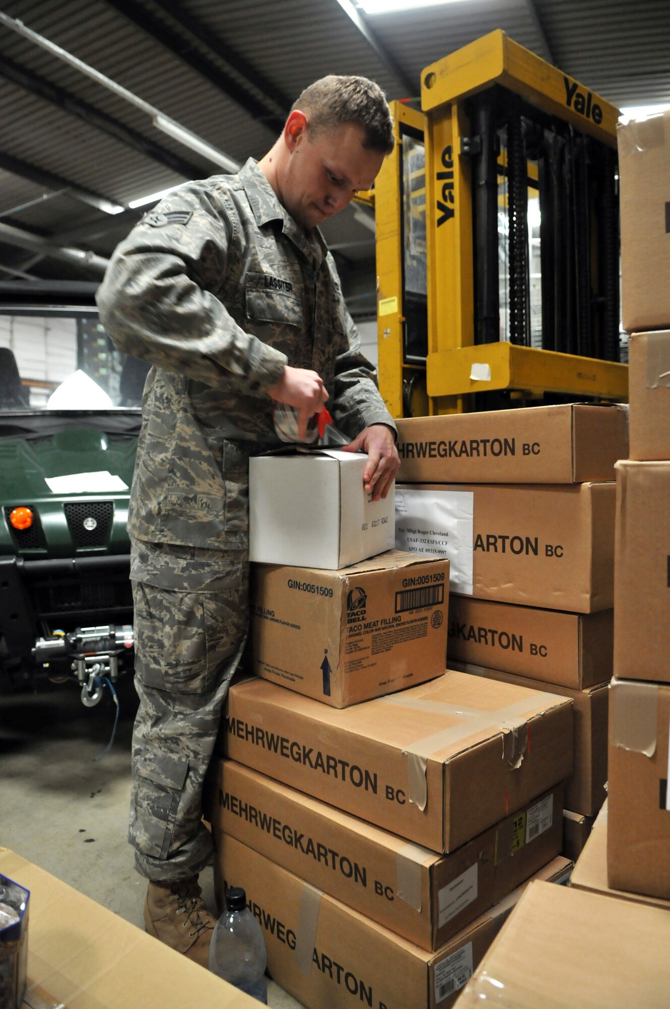 RAF MILDENHALL, England -- Senior Airman Justin Lassiter, 100th Security Forces Squadron, seals a box of cookies Feb. 26.  Airman Lassiter and other volunteers packaged the 1,100 pounds of donated cookies and sent them to servicemembers in the Middle East.  (U.S. Air Force photo by Staff Sgt. Austin M. May)