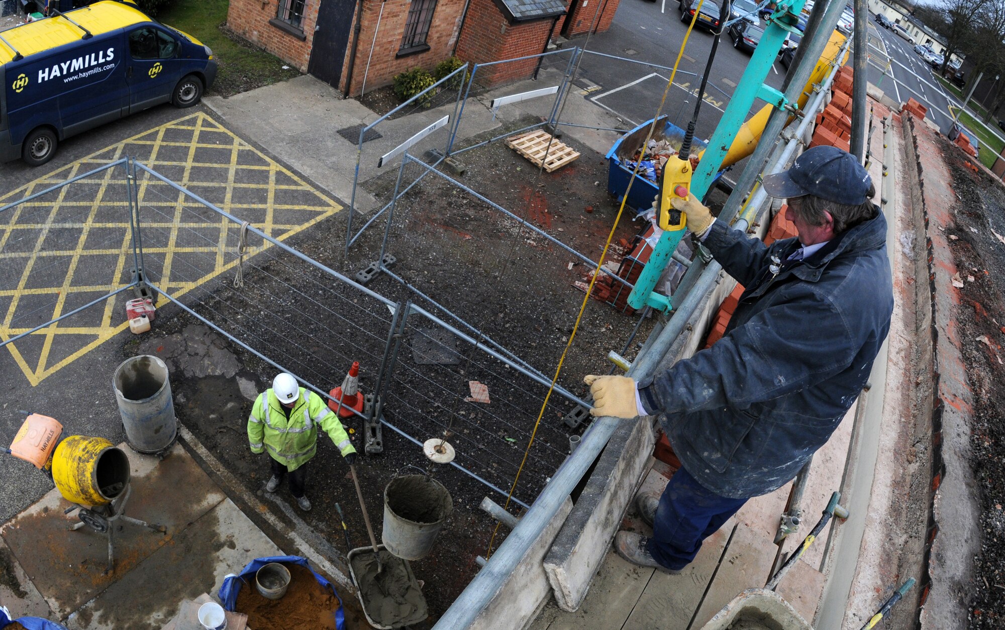 RAF MILDENHALL, England – Dave Garrett, a contracted mason worker, lifts a bucket of cement from Joe Hale during a reroofing project on top of Building 514 March 3. Hundreds of pounds of cement is mixed and used for each roofing project. (U.S. Air Force photo/ Staff Sgt. Jerry Fleshman)